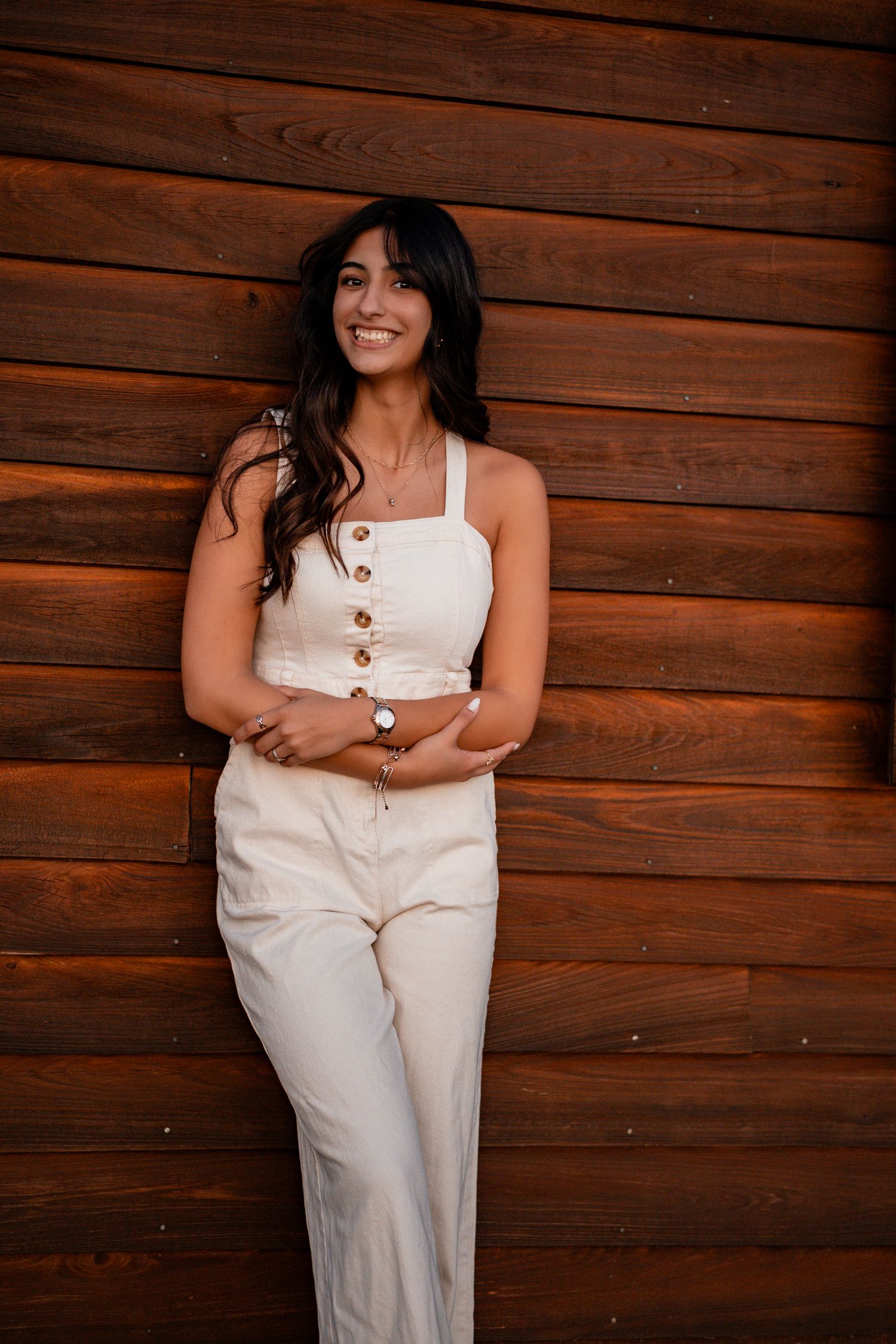 Portrait against rustic wooden wall wearing white summer outfit.