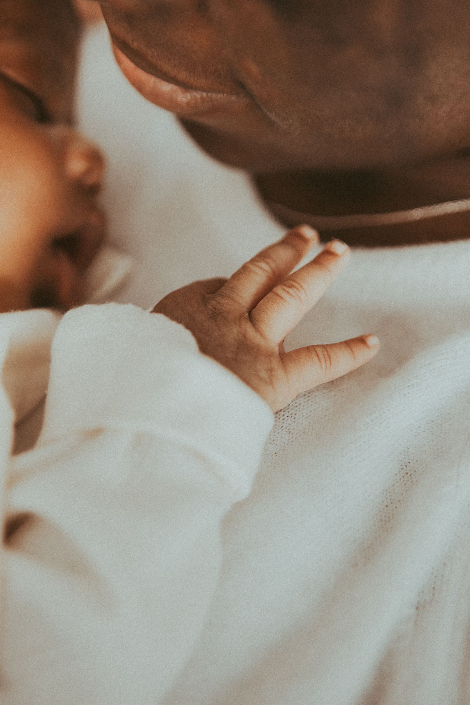 Close-up view of a tender moment showing hands gently touching white fabric in soft lighting.