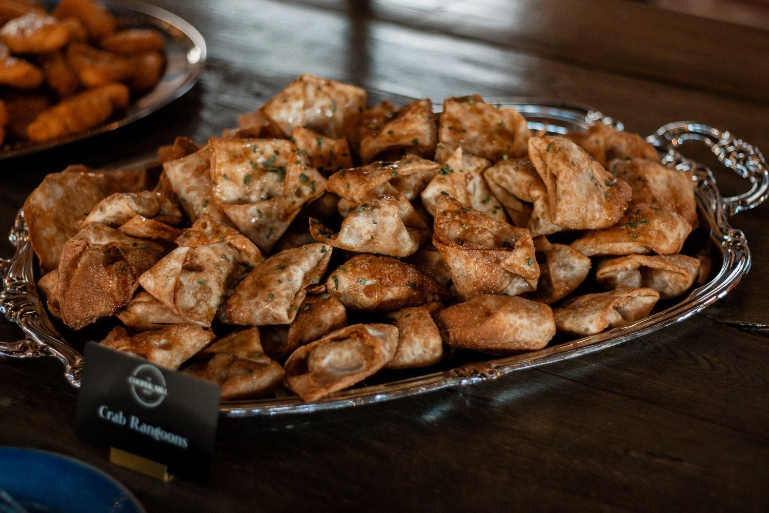 Platter of grilled or roasted chicken wings with seasoning and sauce displayed on dark surface.