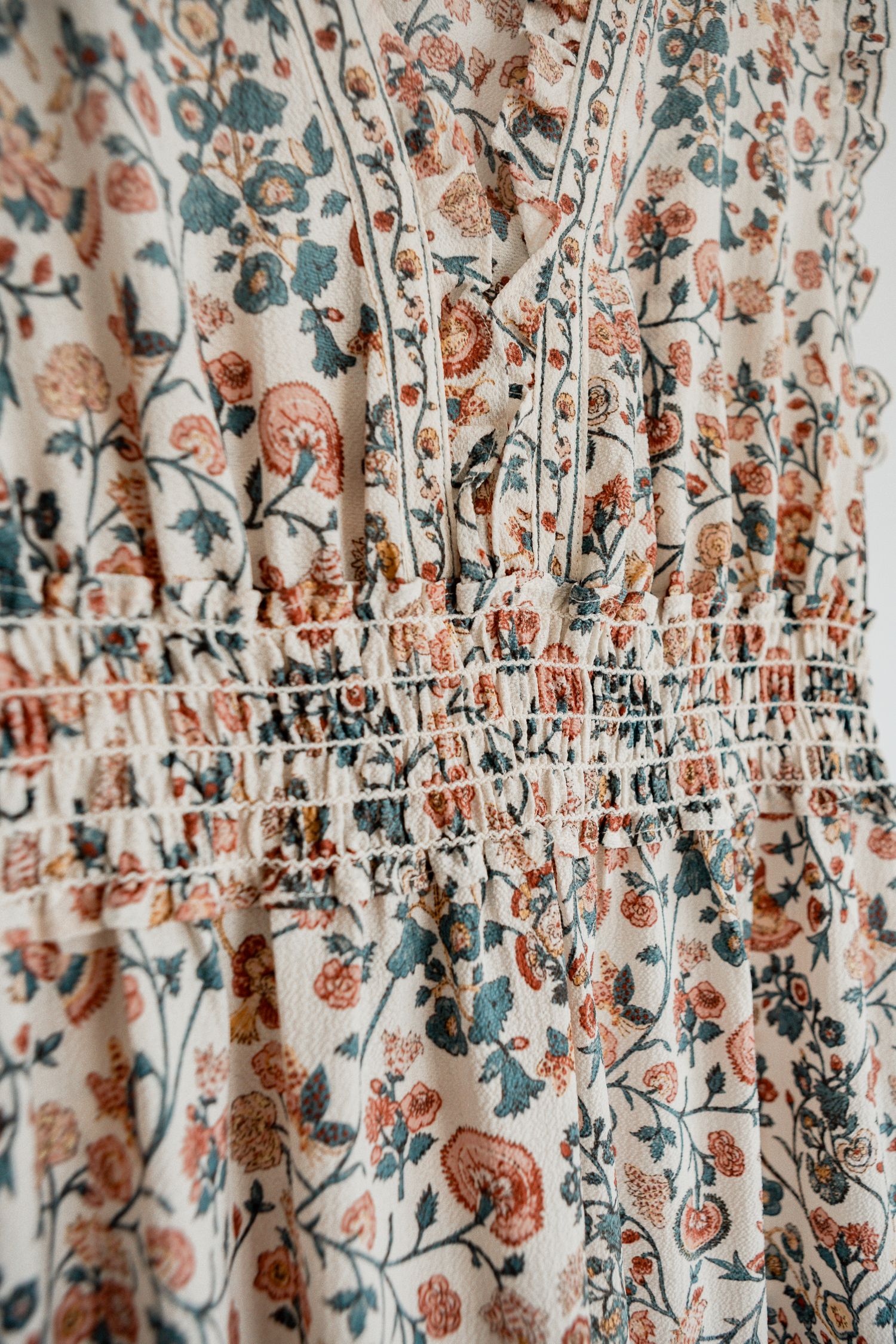 Delicate floral pattern fabric with pink and blue flowers on white background shows gathered ruching details.