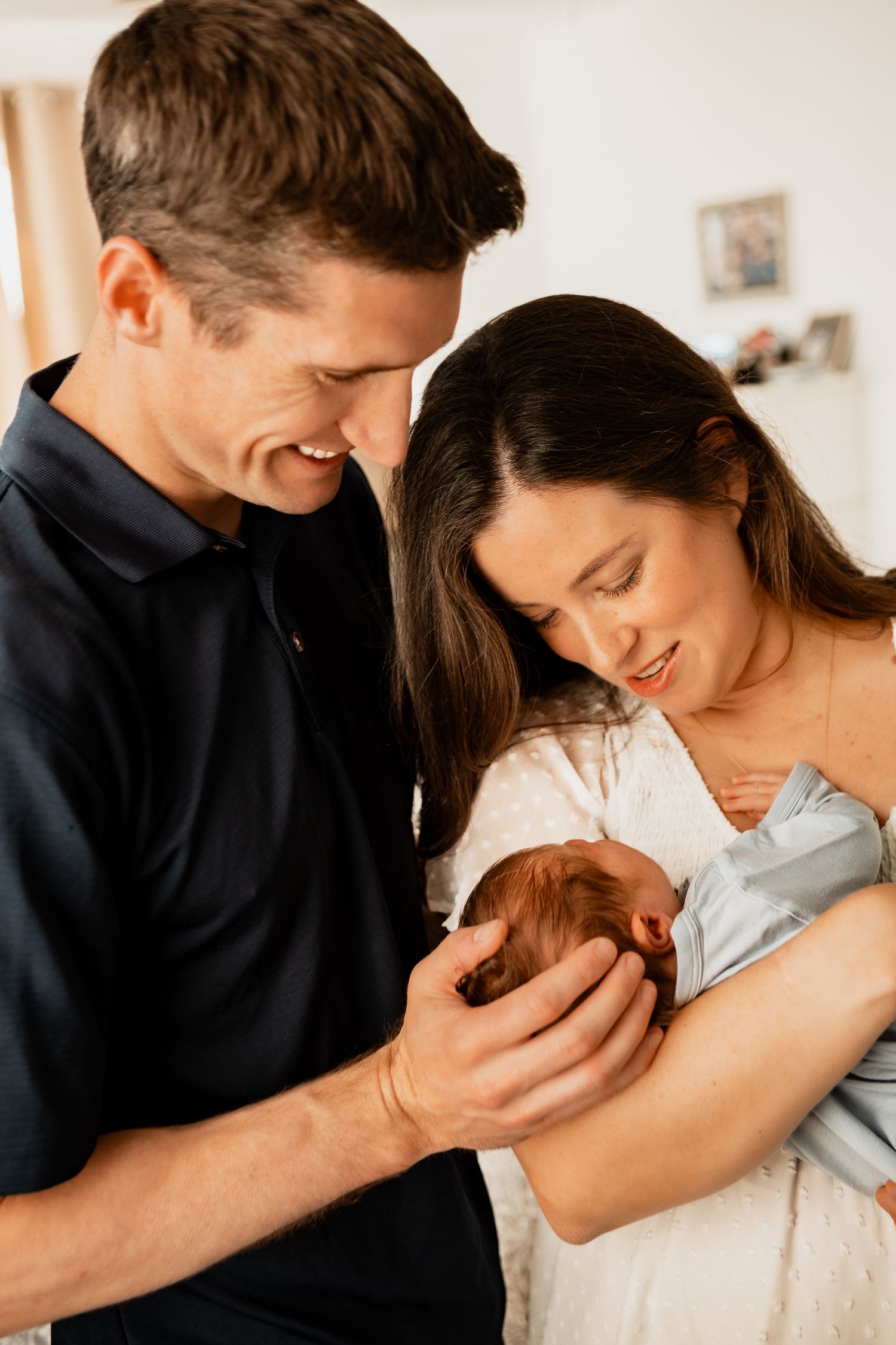 New parents share an intimate moment while cradling their newborn baby.