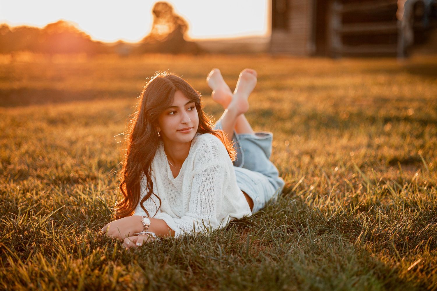 Person lies in golden wheat field illuminated by warm sunset light creating a dreamy summer aesthetic.