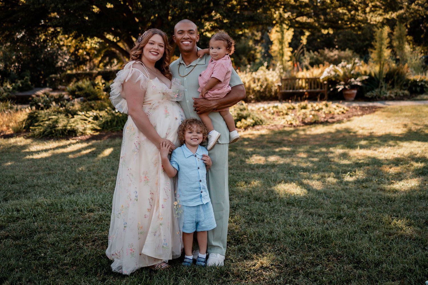 Family members share joyful moments together in a sunlit outdoor setting during a photo session.
