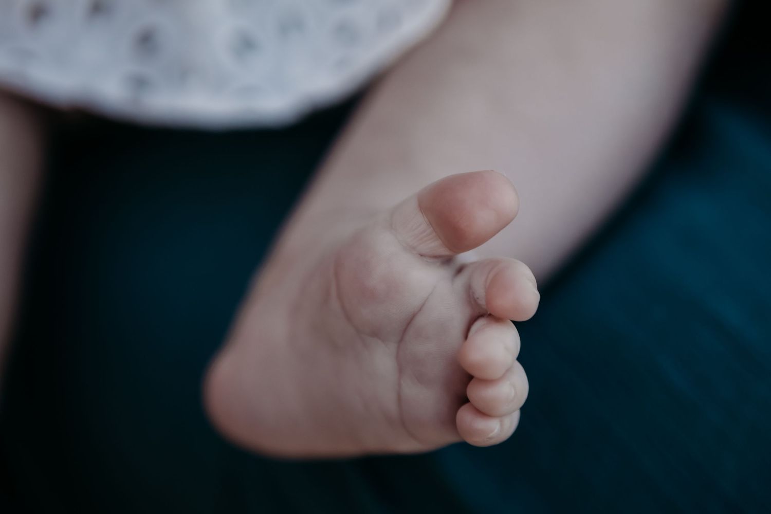 Close-up photo of tiny baby feet against a dark background.