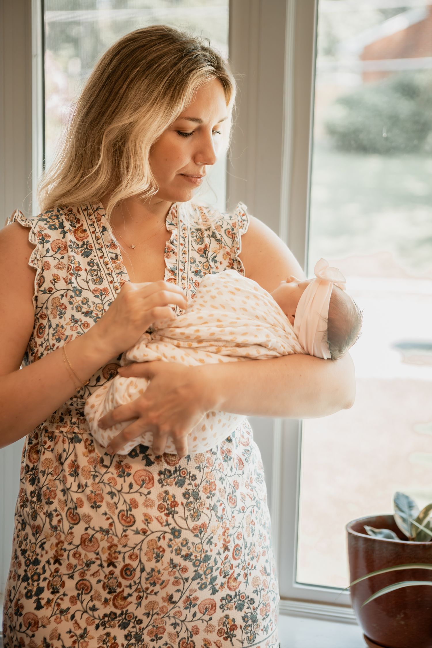 Woman in floral dress touching and embracing her pregnant belly by sunlit window in a series of intimate shots.