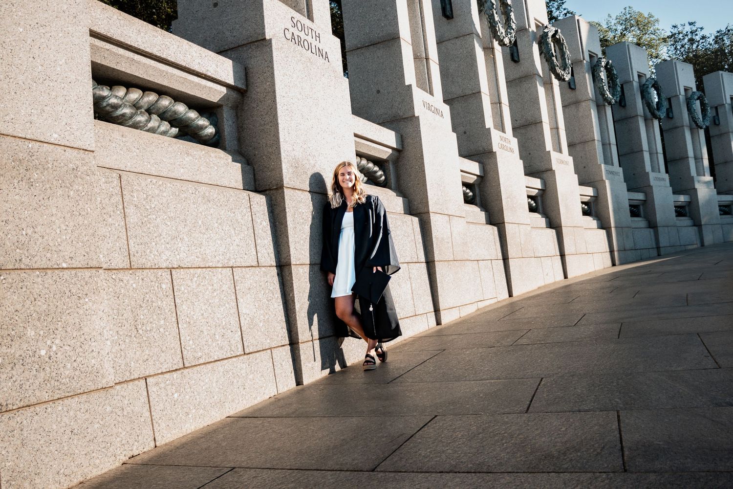 Stone columns and architecture frame graduates posing along a curved walkway.