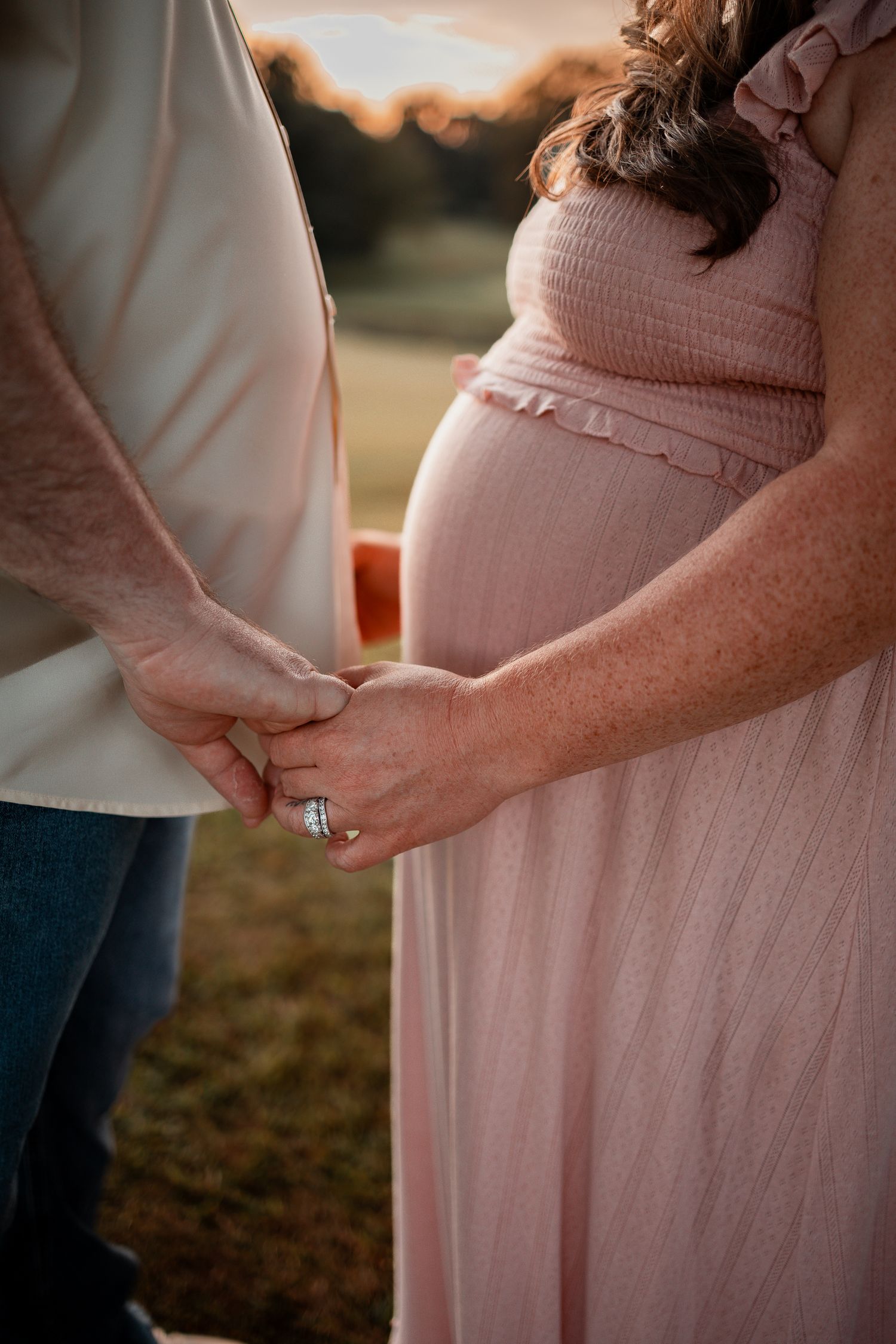A series of maternity photos showing a pregnant woman in a pink dress holding her baby bump at sunset.