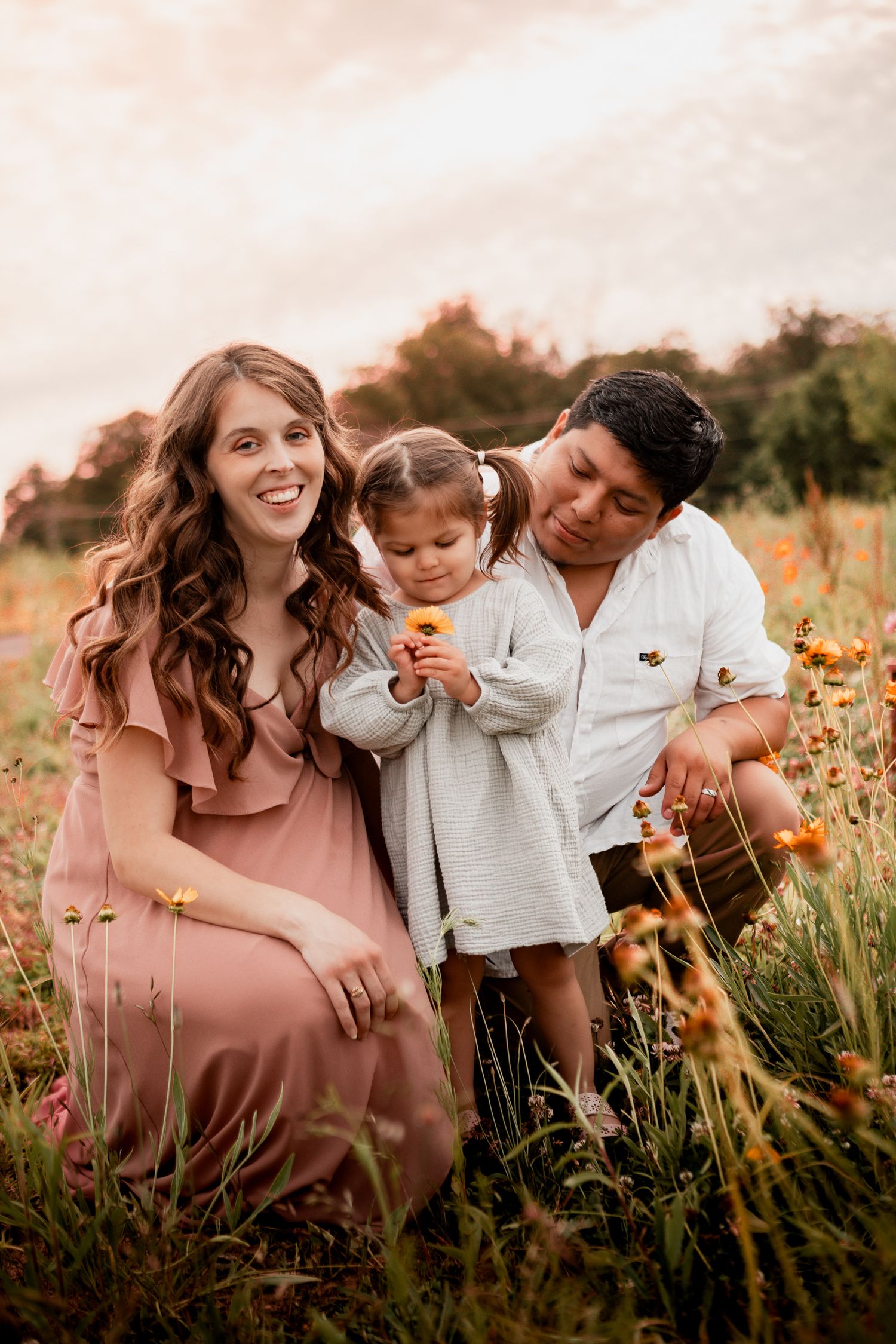 A family shares a tender moment together in a field of wildflowers during golden hour.