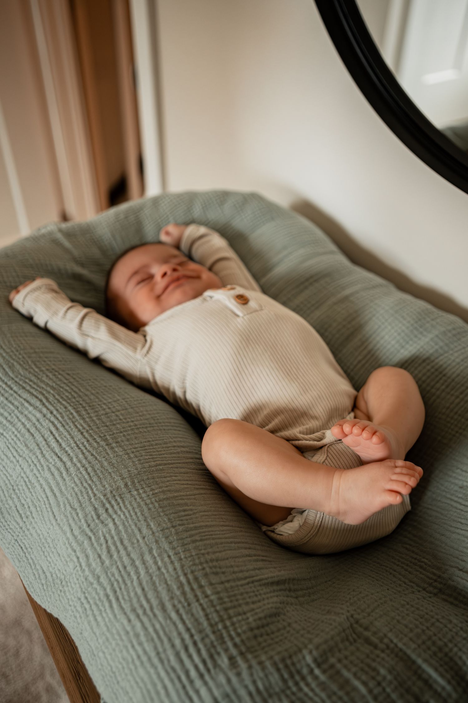 Series of images showing a peaceful sleeping baby in a cream onesie on a textured gray blanket.