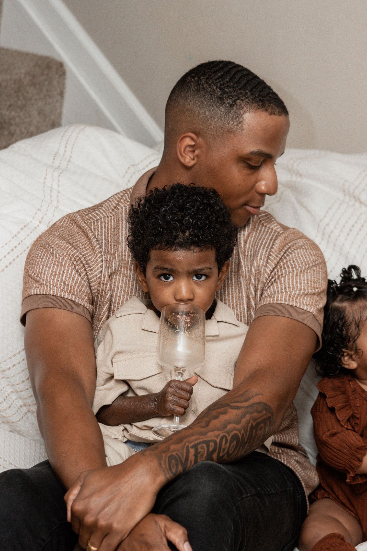 A parent and child share a tender moment while relaxing together on a white couch.