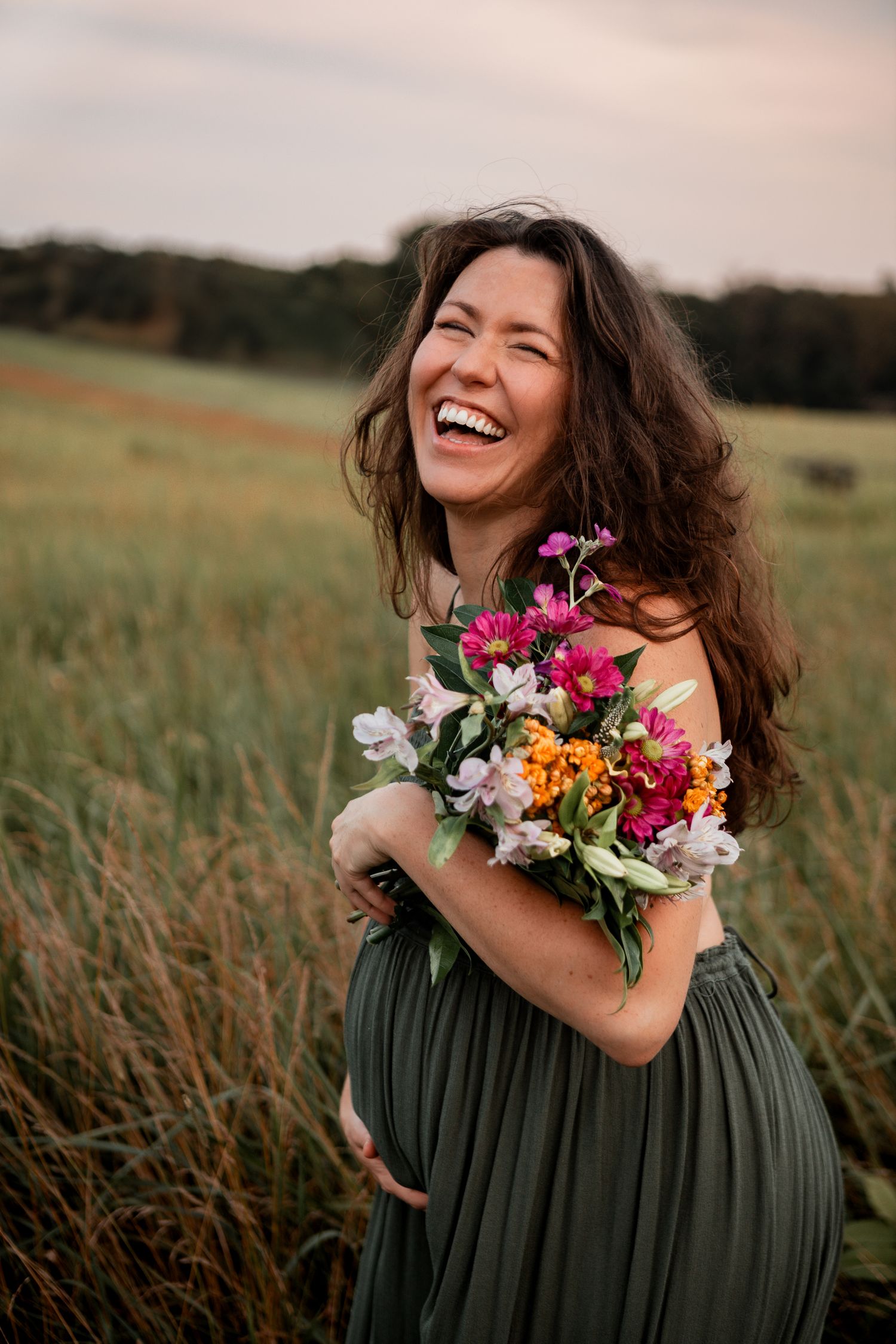 A joyful moment captured in a field at sunset with a vibrant bouquet of colorful wildflowers.