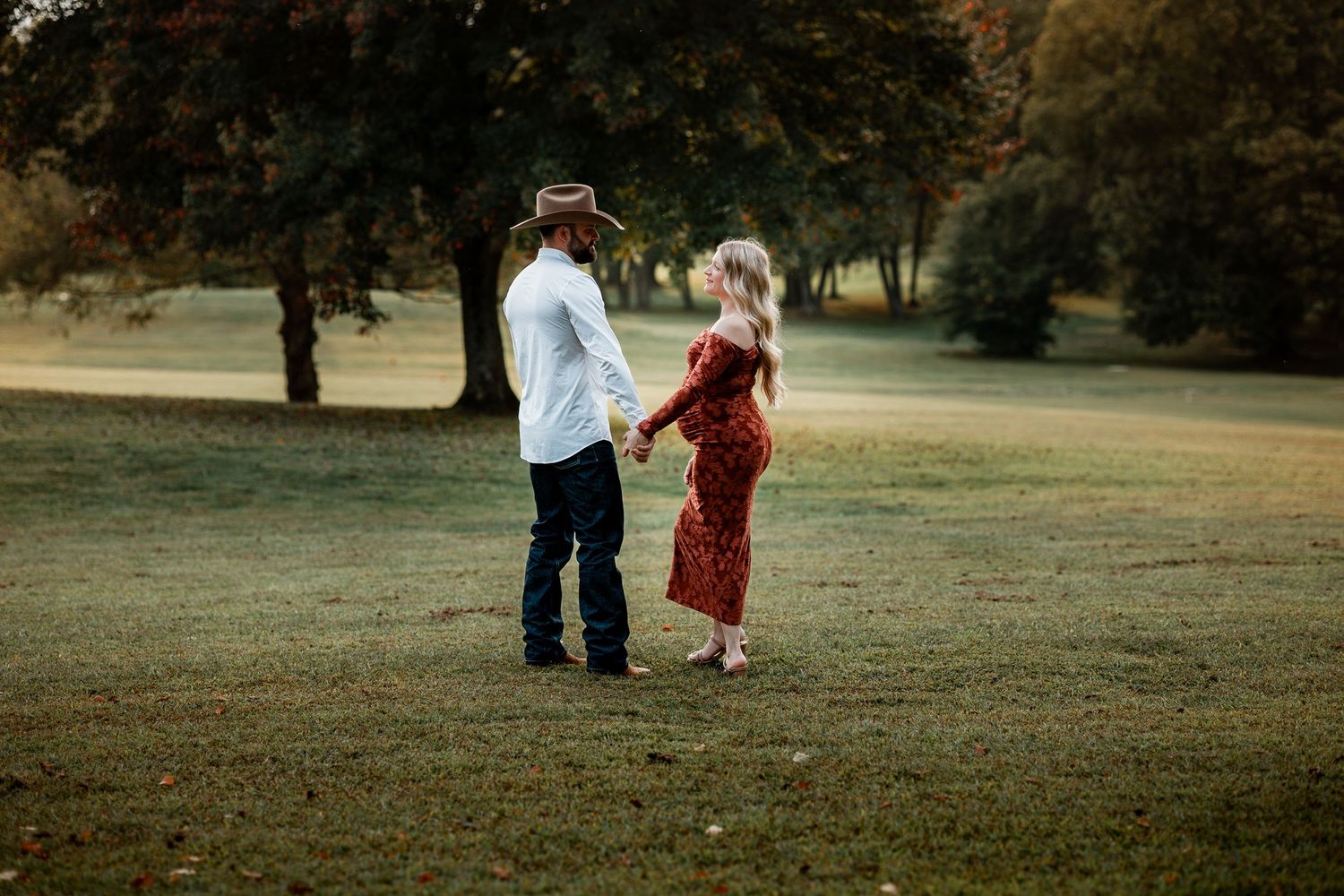 A romantic sunset photoshoot in a grassy field with warm autumn lighting.