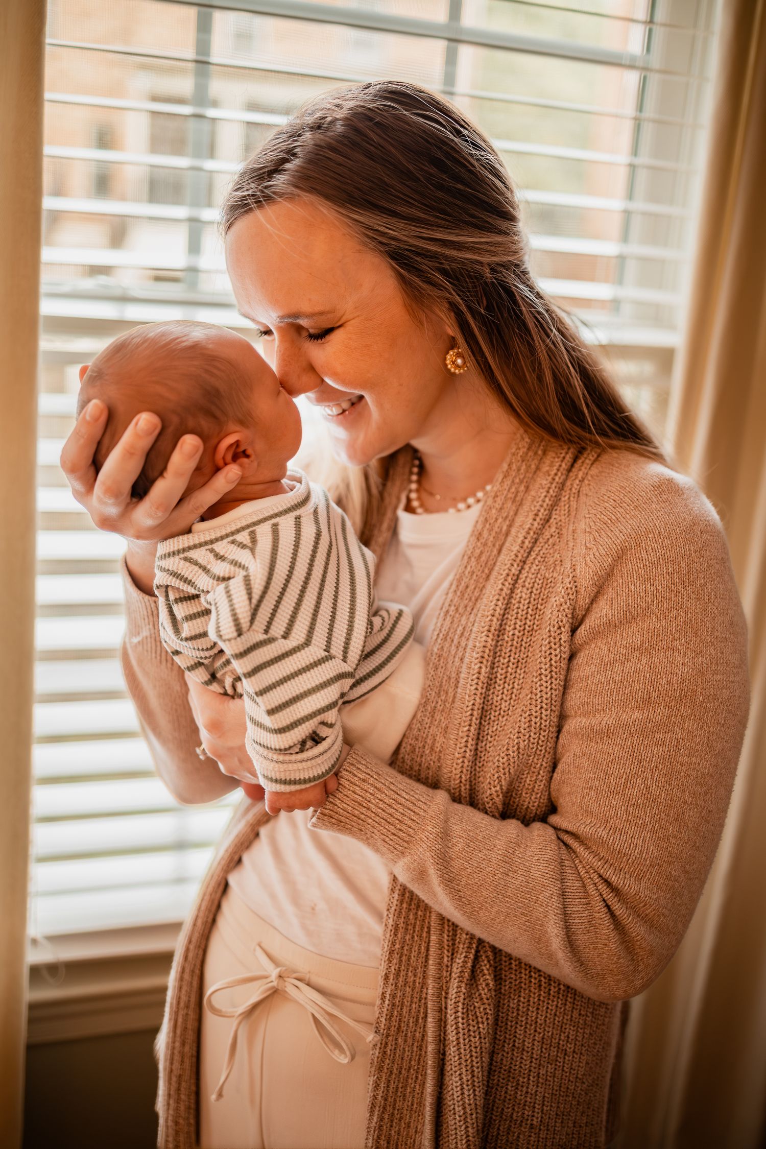 A tender family moment captured in warm lighting as they embrace their newborn baby.