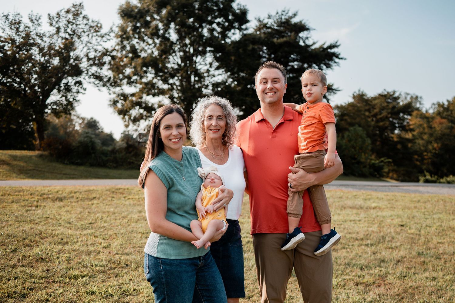 A group of people standing together in a grassy field during golden hour sunset lighting.