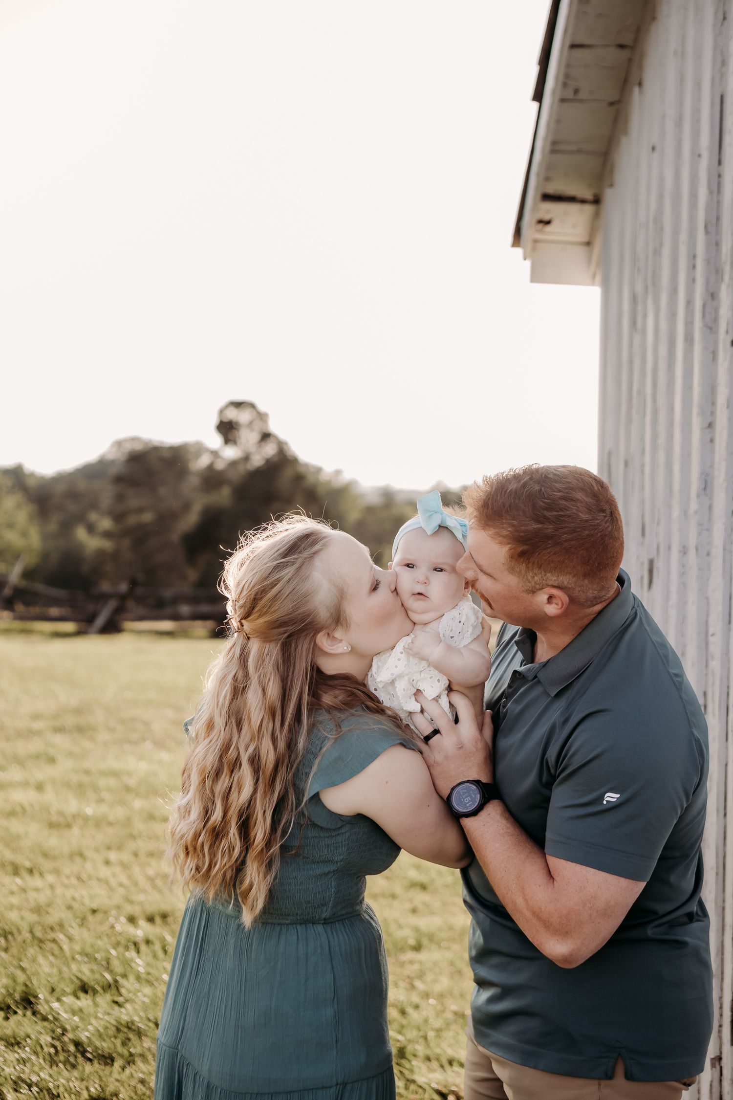 Sweet family portraits captured between white columns with a baby wearing a blue bow.