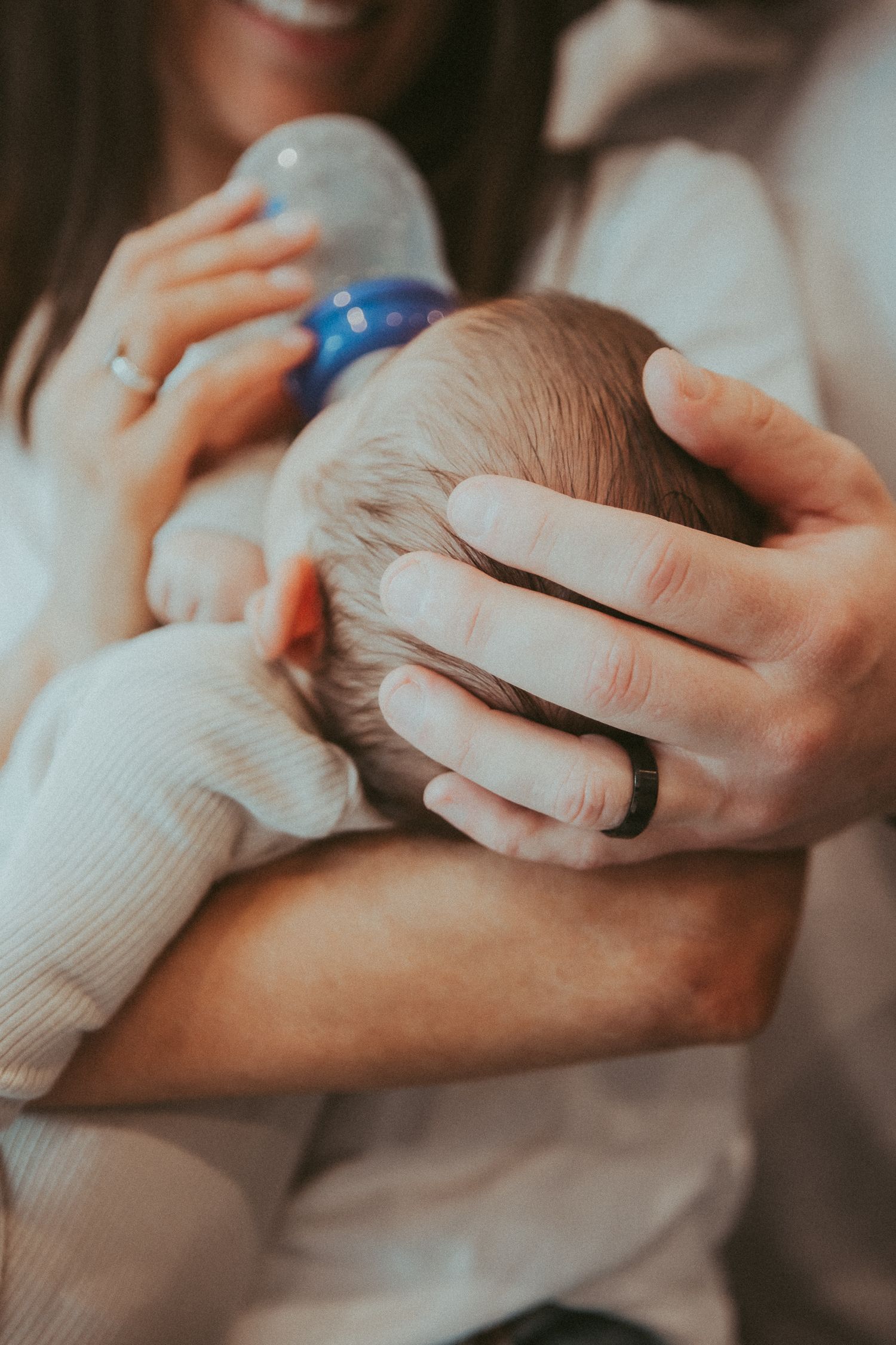 Close-up of hands holding and feeding a small baby.