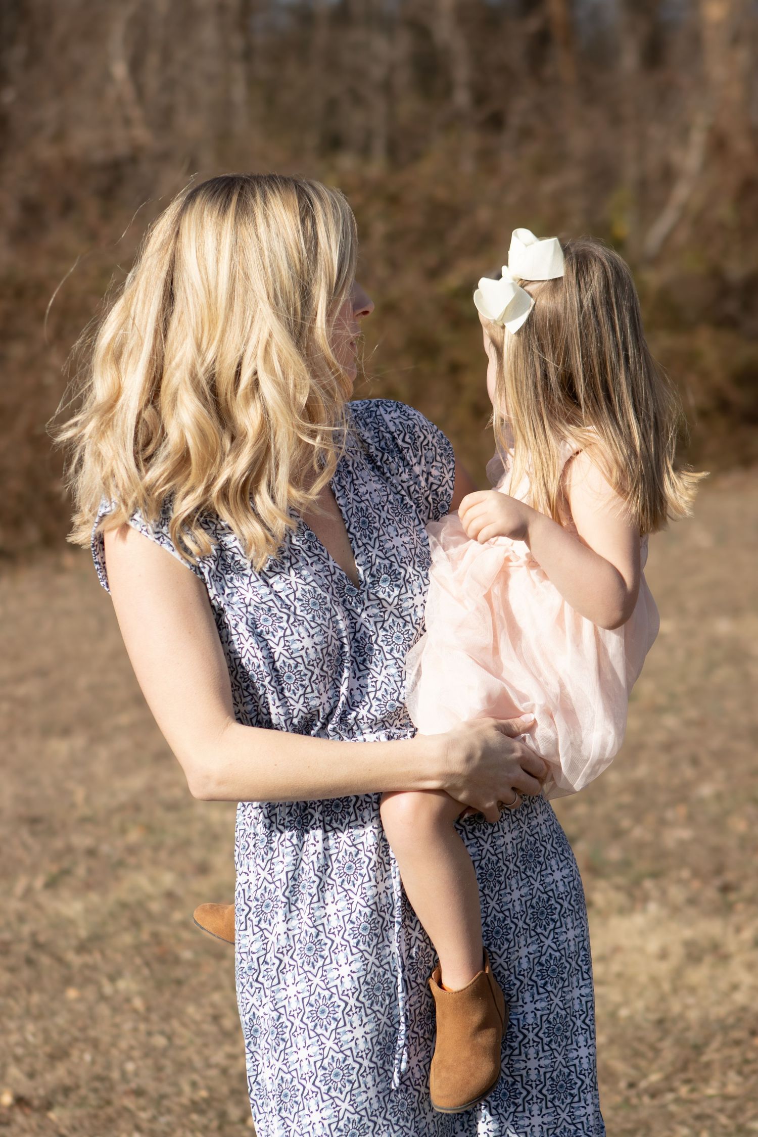Children in matching blue dresses sharing a sweet moment together in nature.