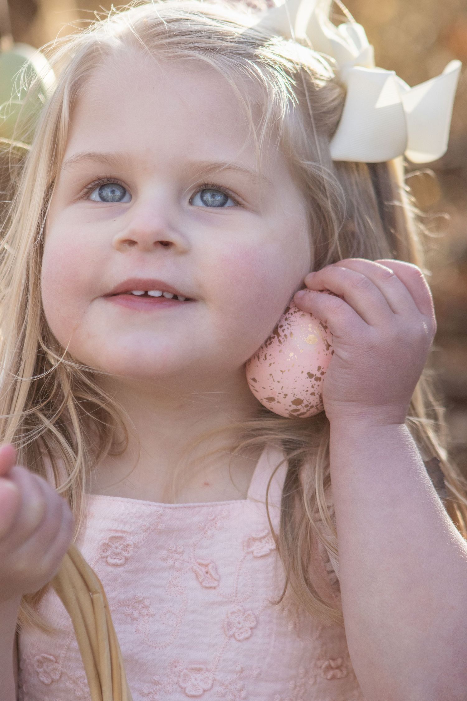 Close-up sequence of a child with bright blue eyes wearing a pink dress in golden sunlight.