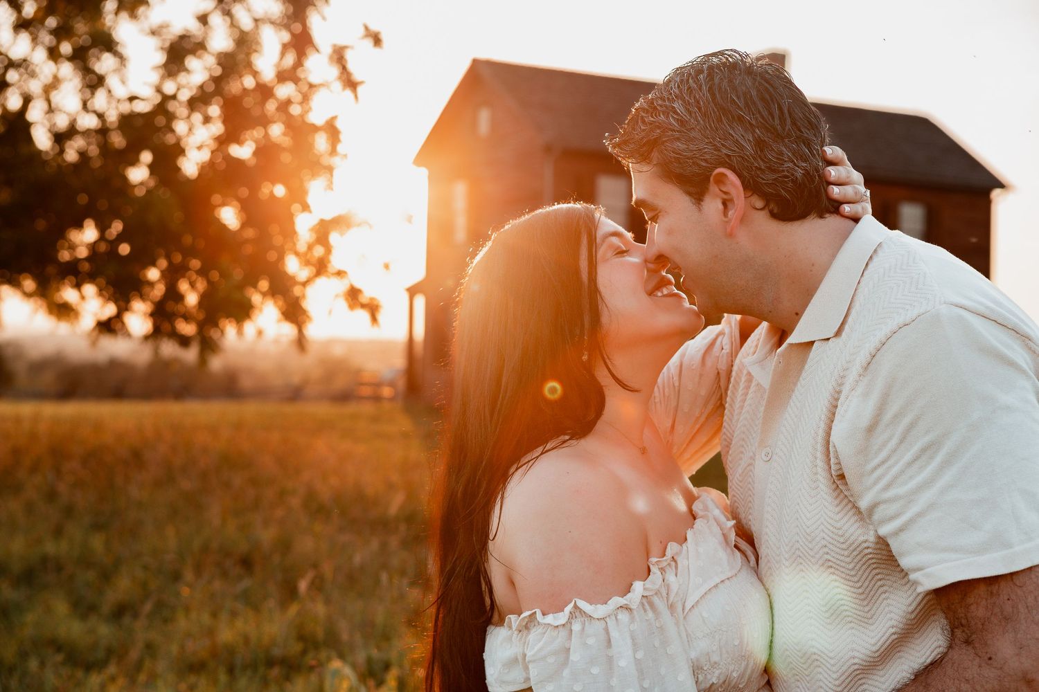A romantic couple sharing an intimate moment in a golden sunset with a rustic barn in the background.