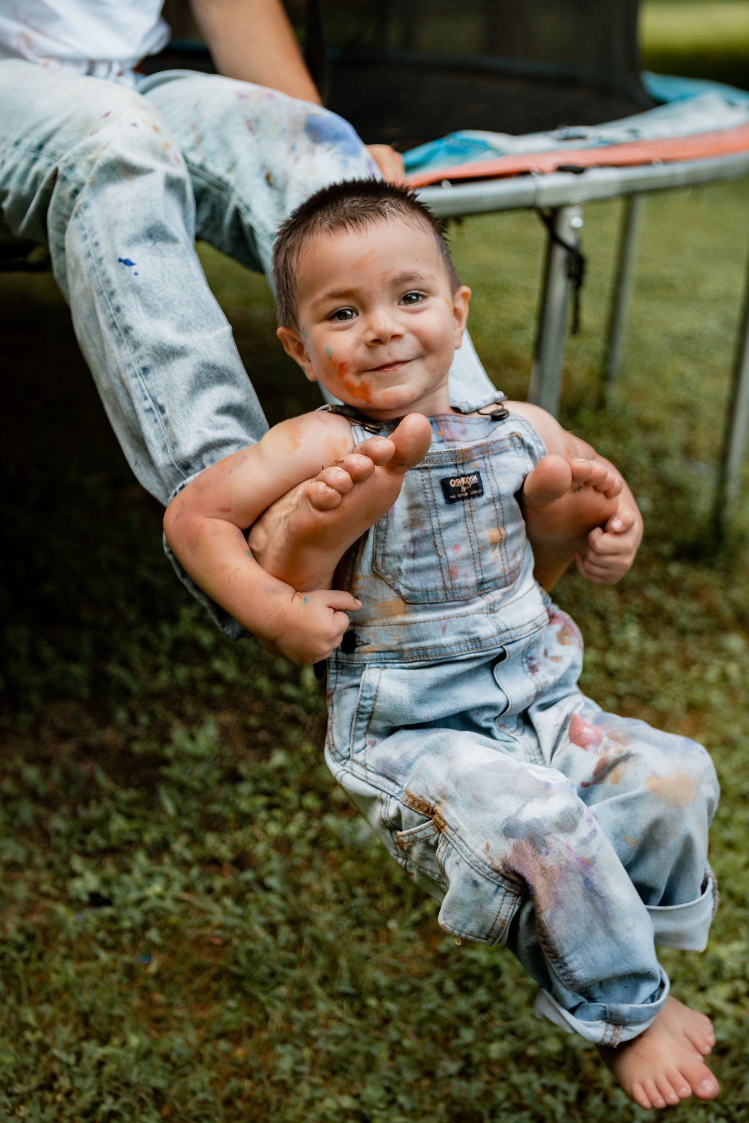 Joyful sequence in overalls outdoors showing playful painting activity.