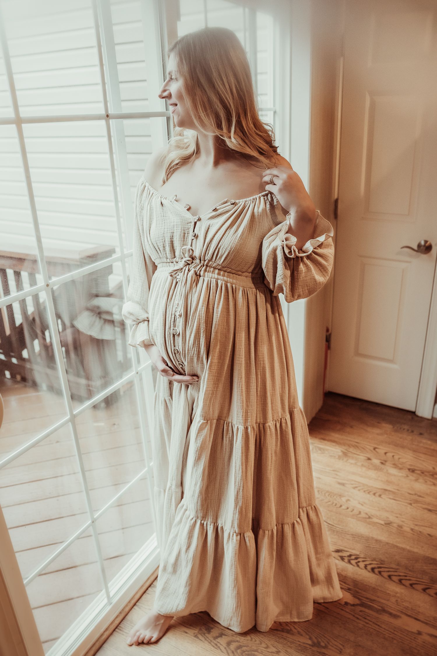 A flowing beige linen dress with bow details and tiered skirt shown from multiple angles on hardwood floors.