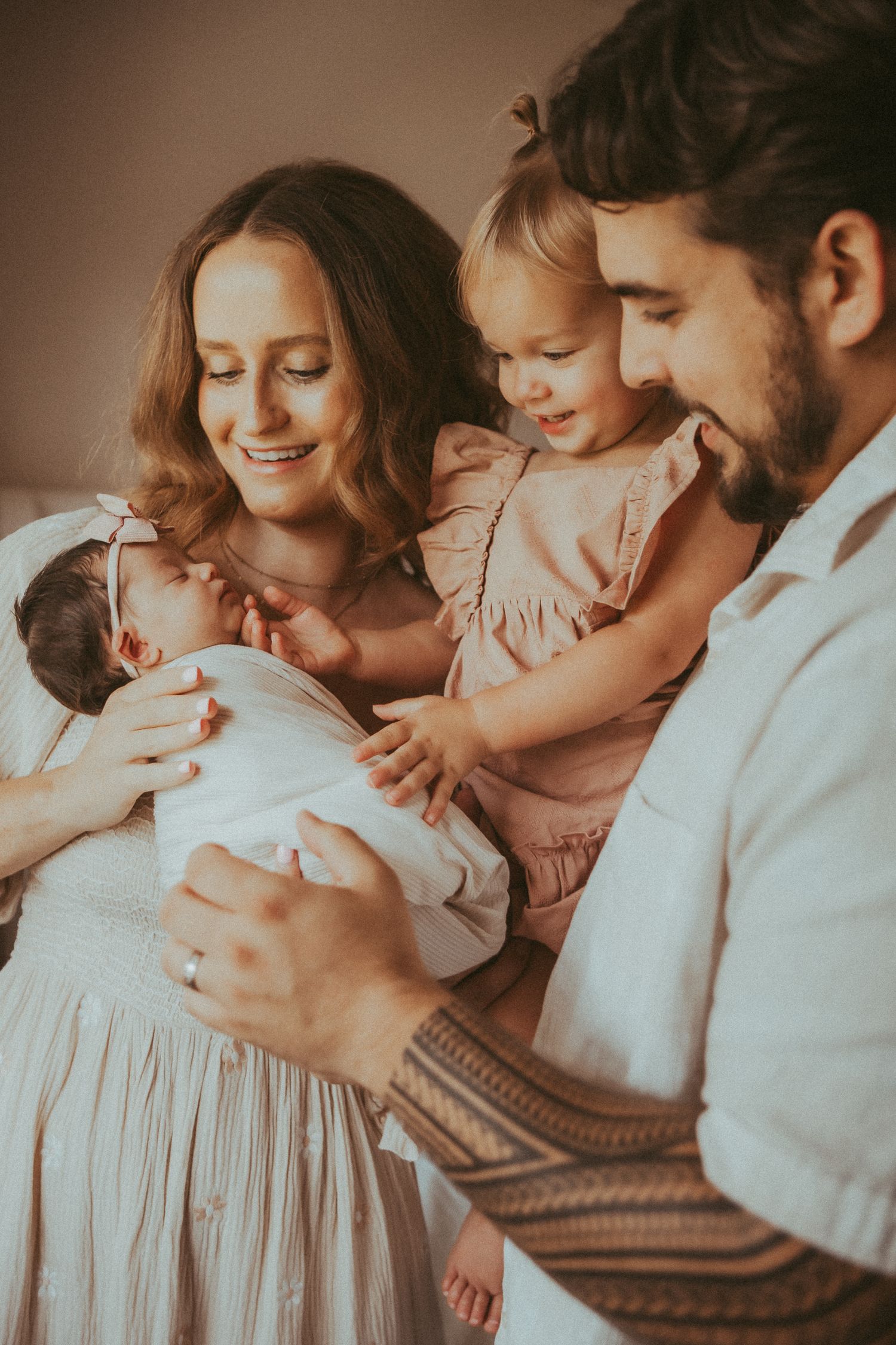 Intimate family portrait series showing tender moments between parents and child in soft, warm lighting.