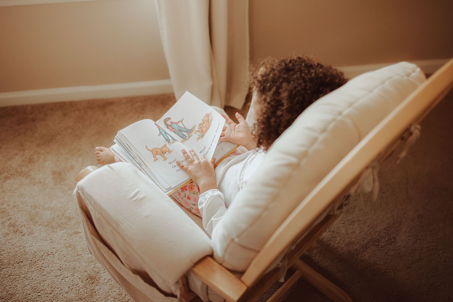 A person lies on a brown couch reading a book in a cozy living room setting.