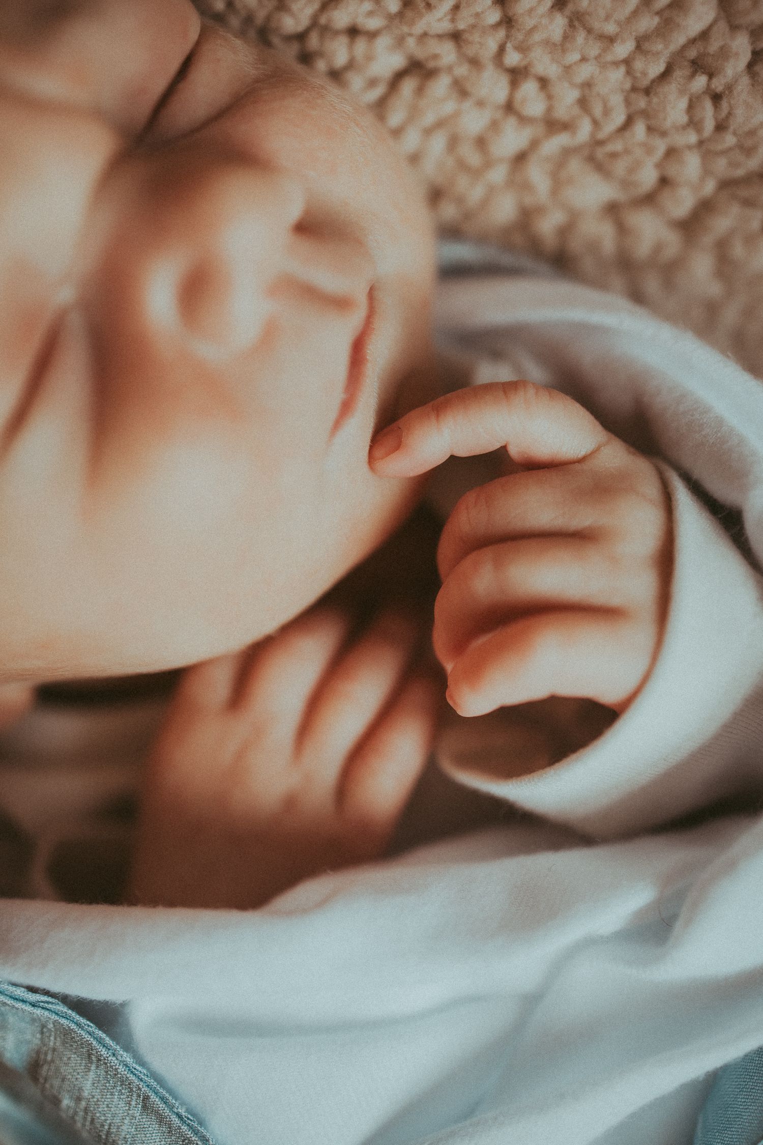A close-up series of images showing a baby's tiny hands grasping and reaching against soft white fabric.