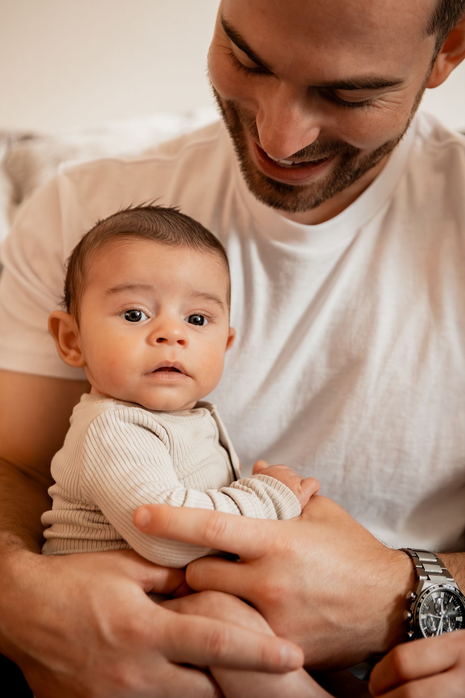 A tender moment captured in a series of photos showing a parent bonding with their infant in white clothing.