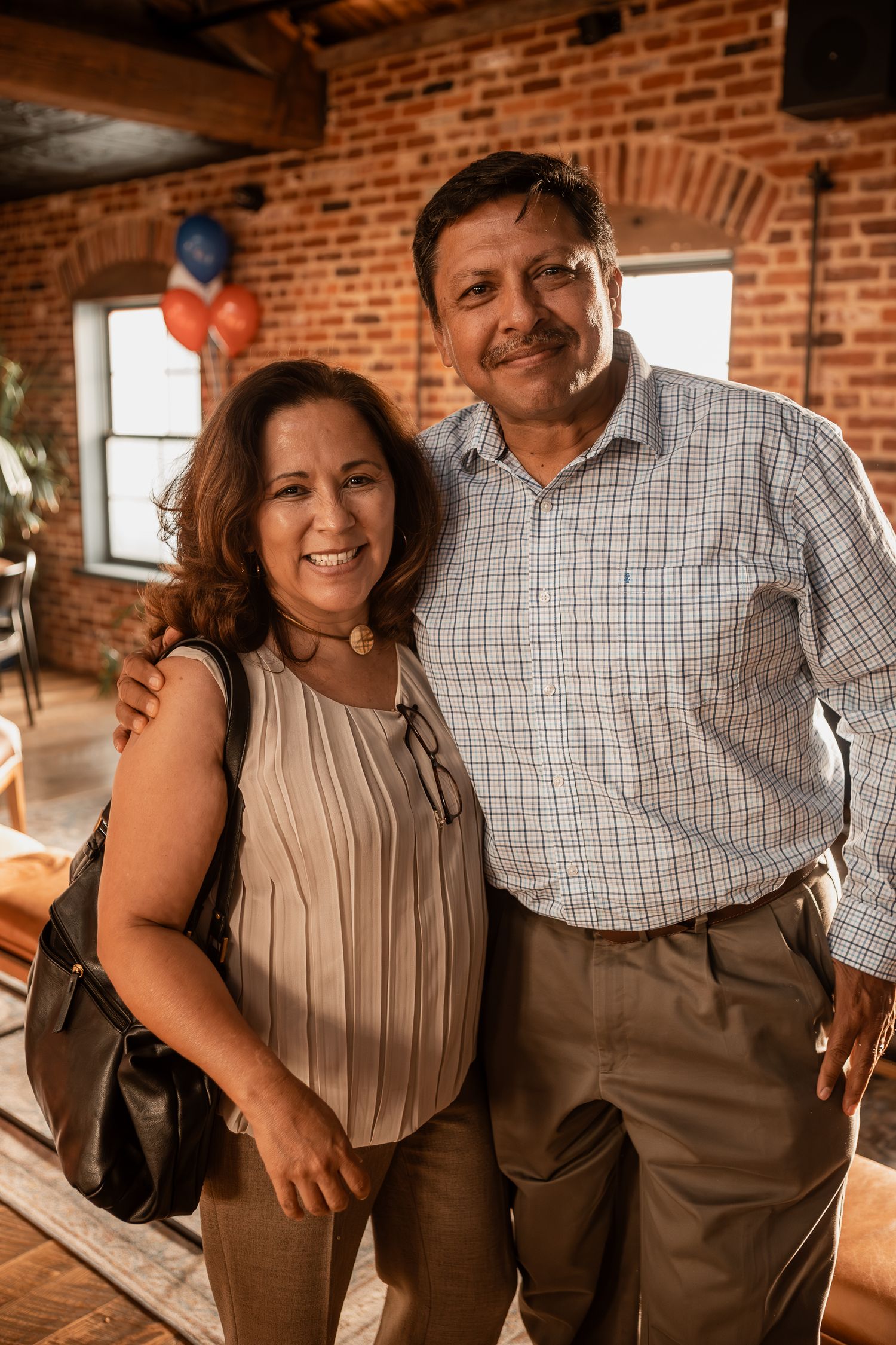 Couple in casual attire sharing a warm moment against exposed brick walls.