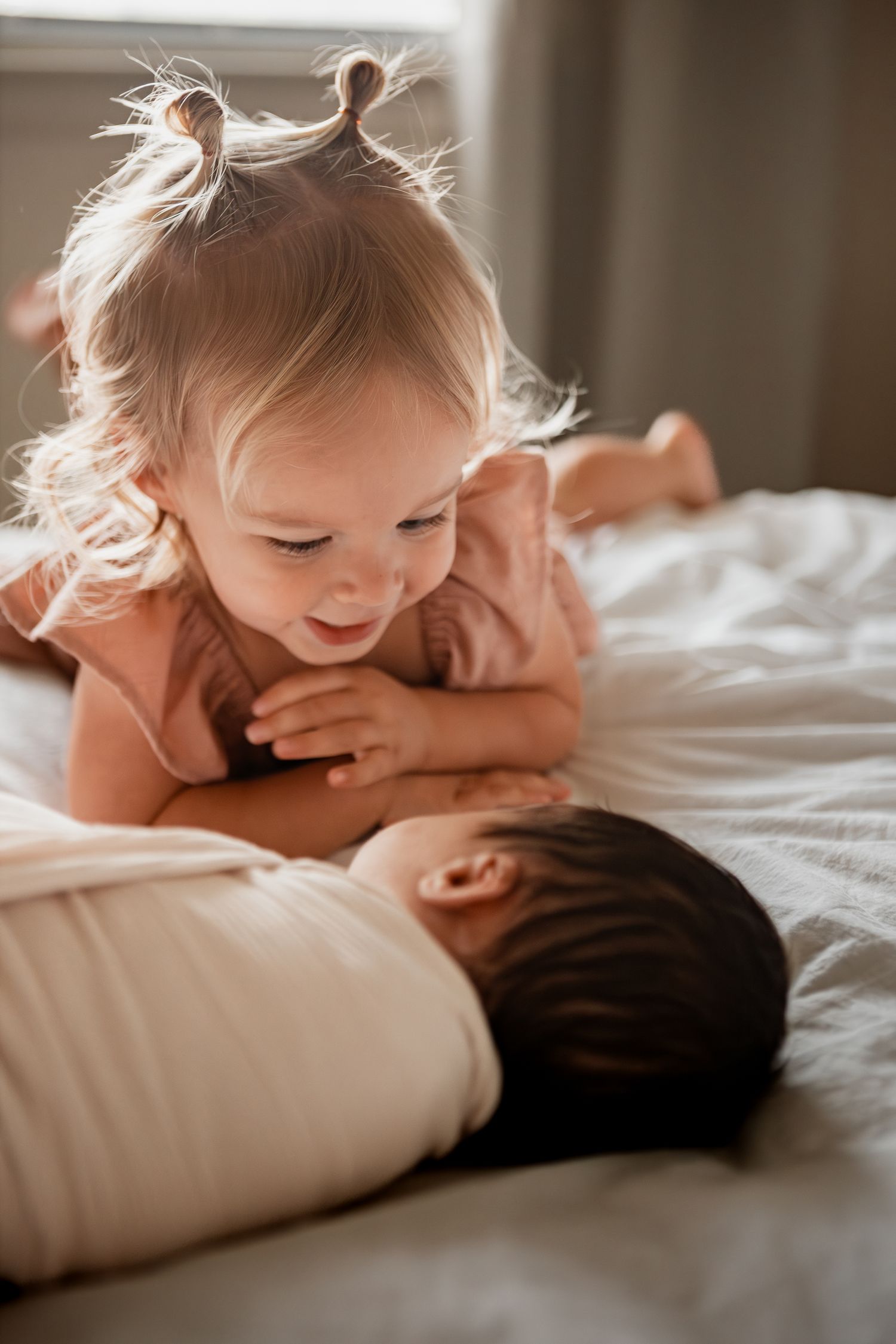 Five sequential images show tender interactions between a young child with light hair and an adult lying together on white bedding.