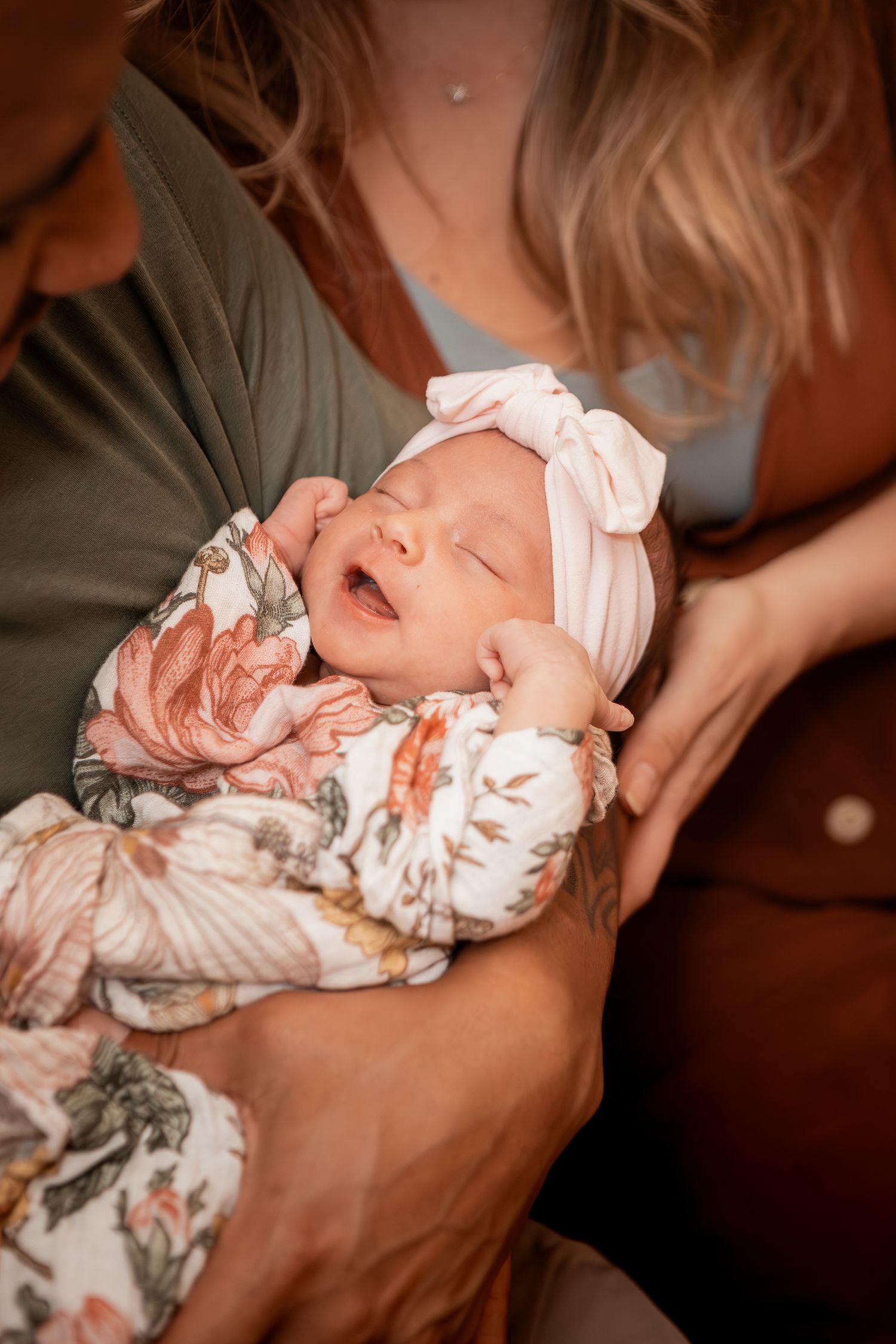 A series of photographs shows a sleeping newborn baby wrapped in a floral swaddle blanket.