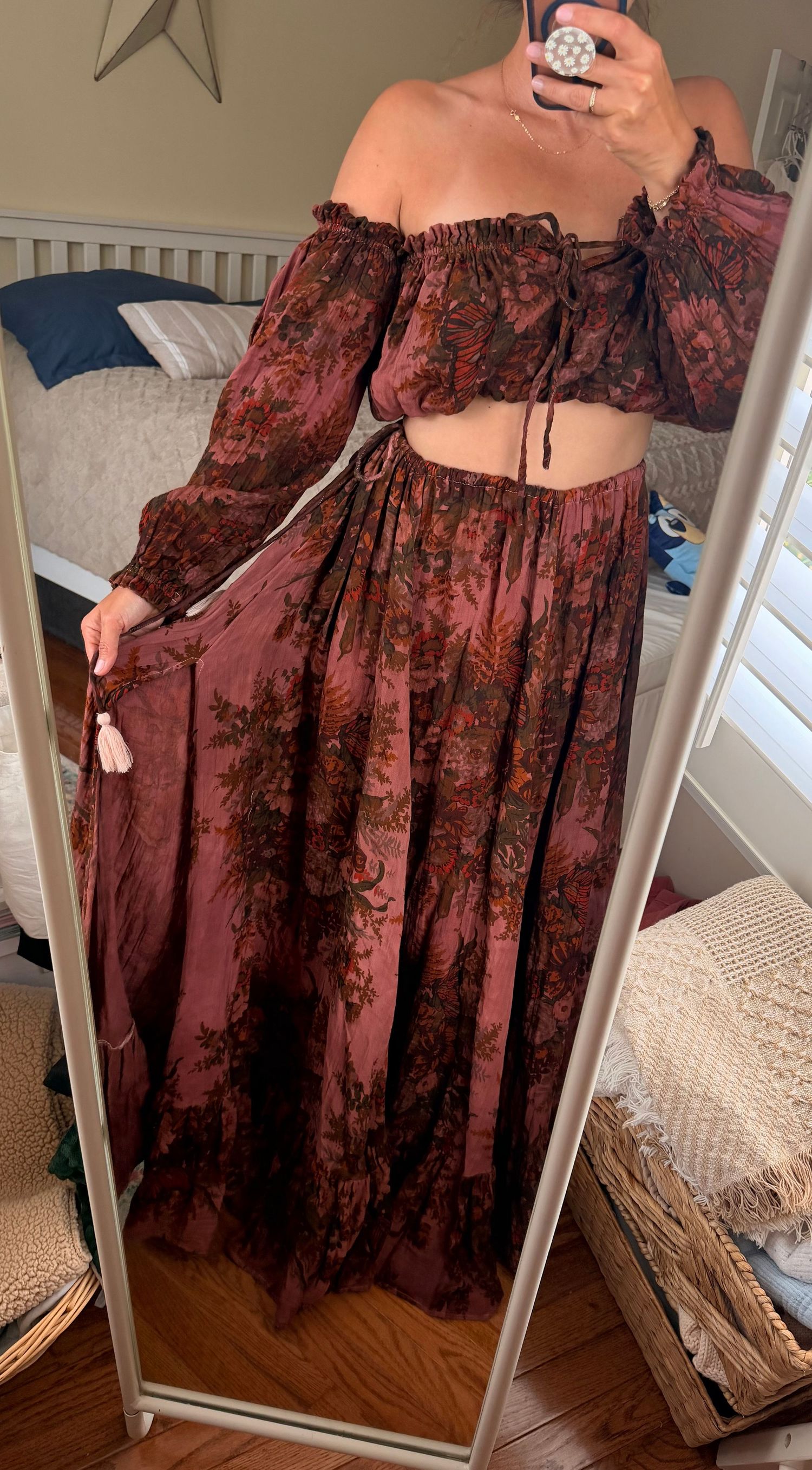 Woman wearing a bohemian floral two-piece set with off-shoulder crop top and maxi skirt in rust tones.