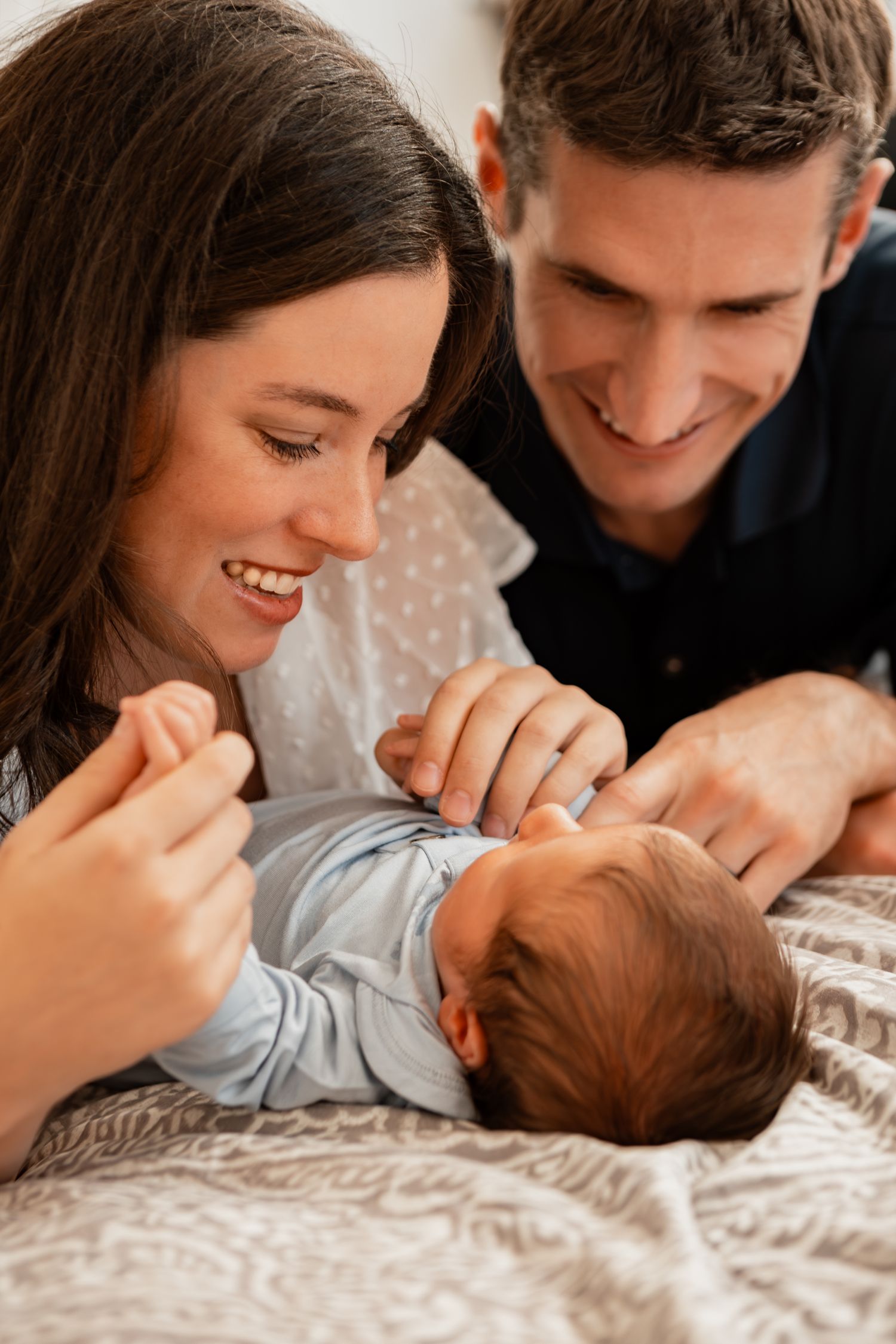 Sweet family photo session captures loving moments shared on a bed with patterned bedding.