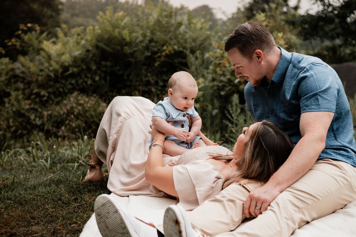 Family enjoying tender moments together during an outdoor photo session in a natural setting.