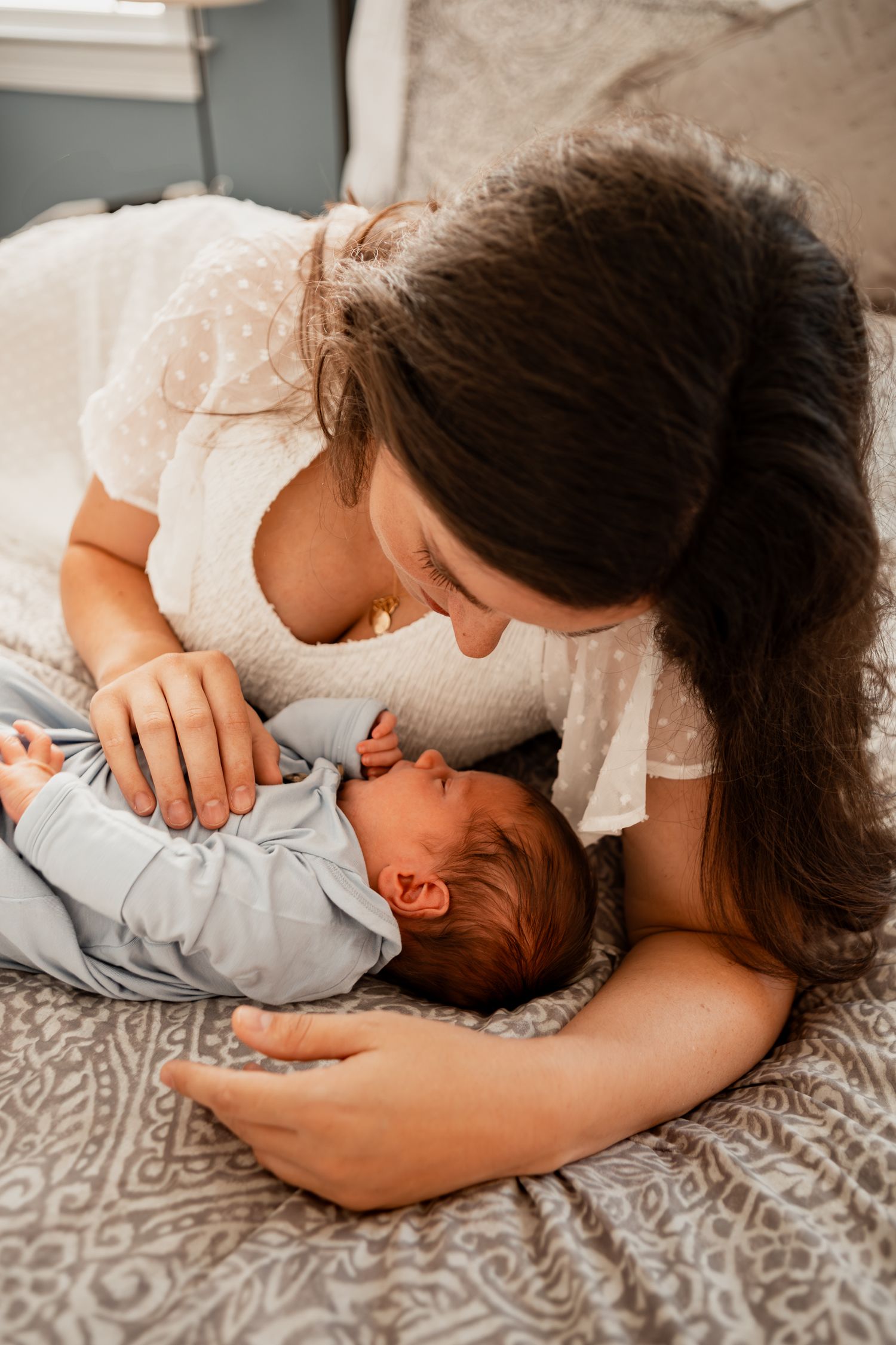 Intimate candid lifestyle photos show tender family moments on a gray patterned blanket.