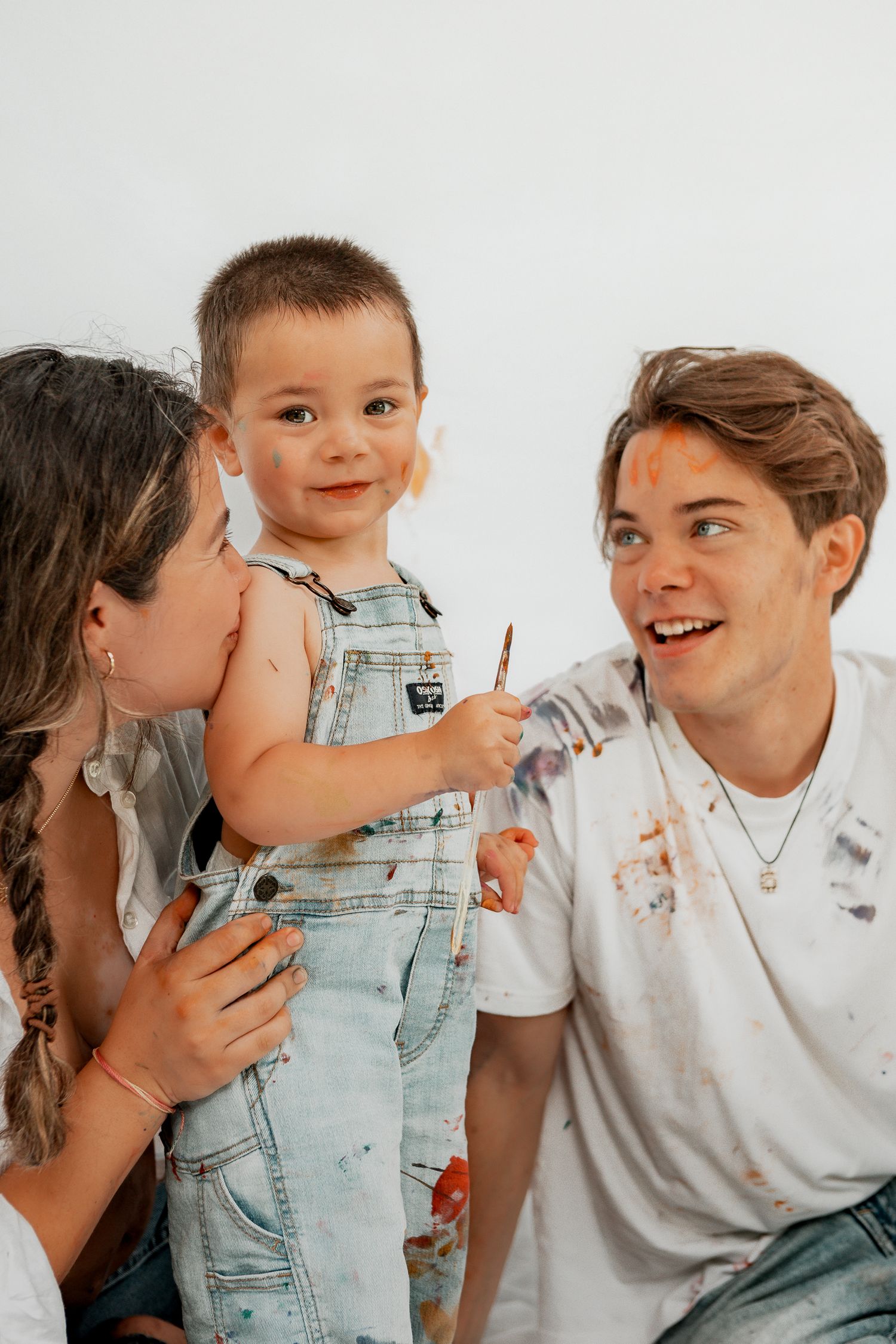 Sweet family moment showing affection and playful kisses while wearing casual denim and white clothing.