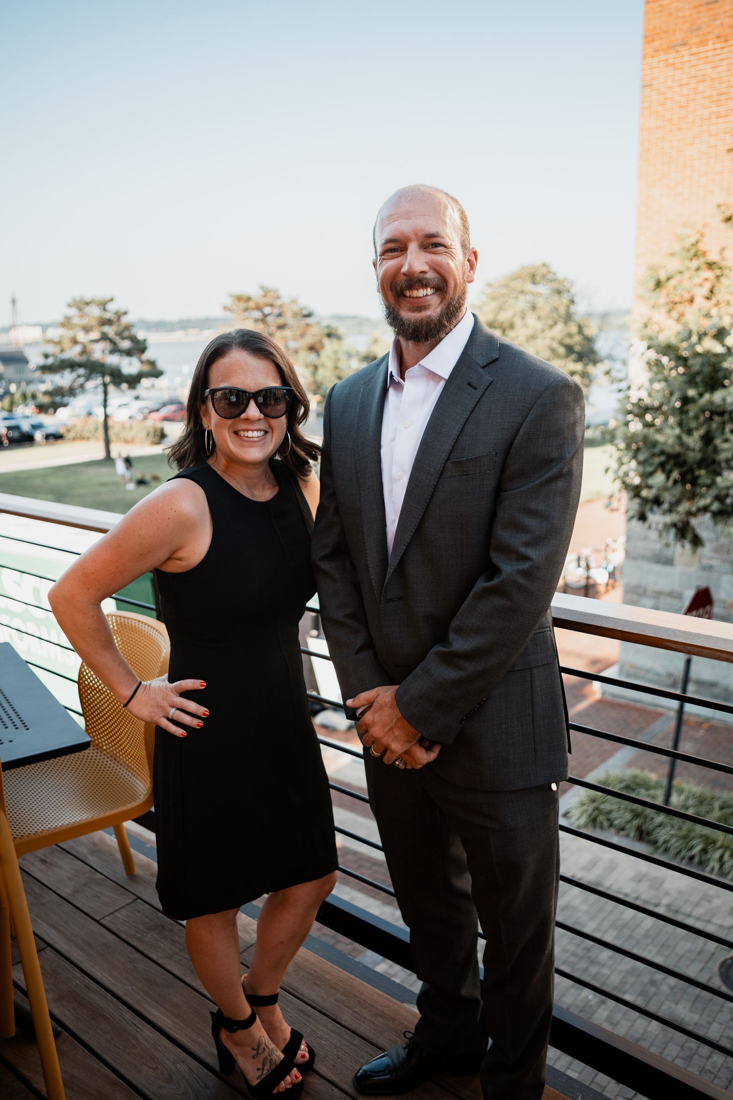 Couple posing together on an outdoor deck with black and formal attire.