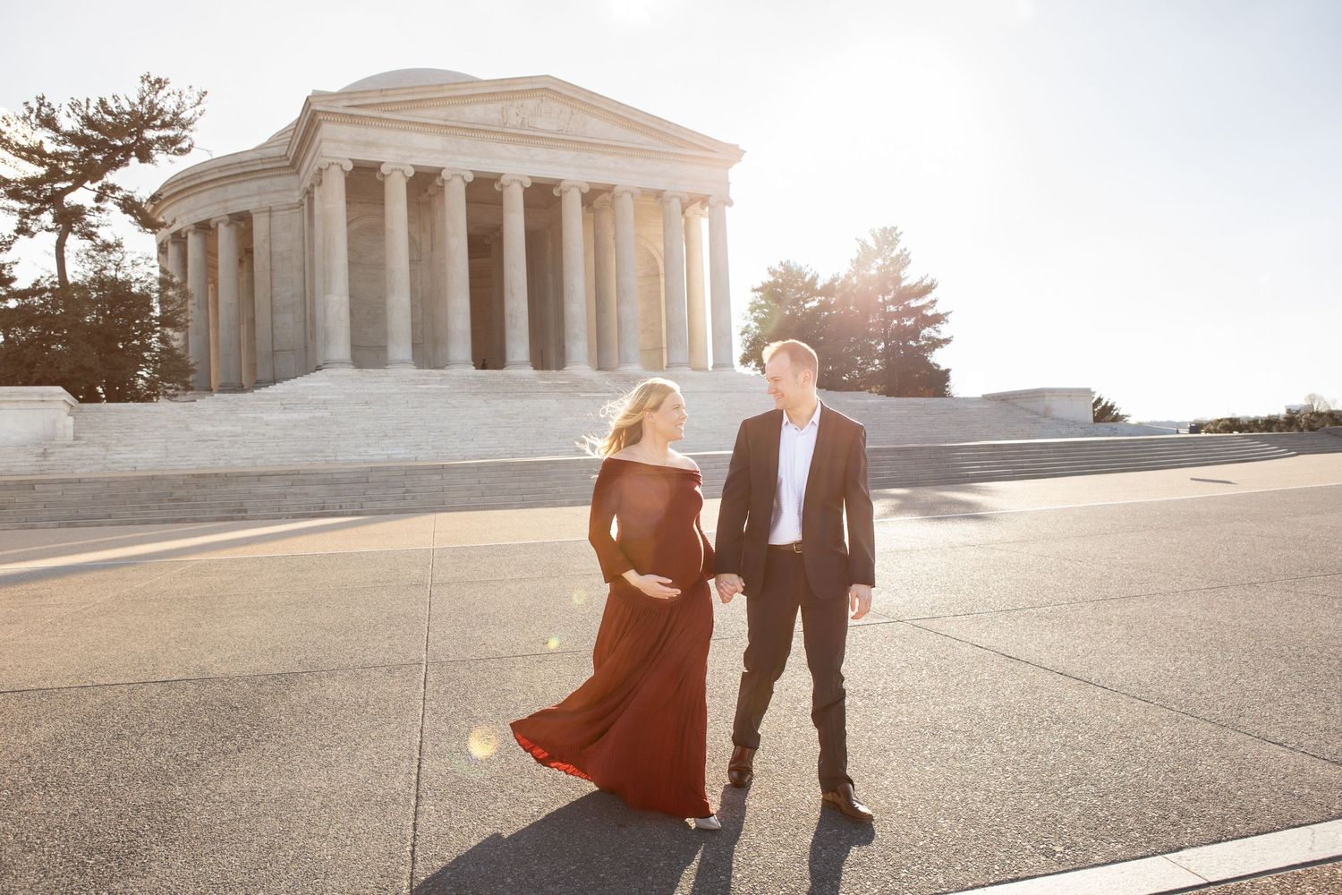 A couple in formal attire poses at sunset in front of the Jefferson Memorial in Washington DC.