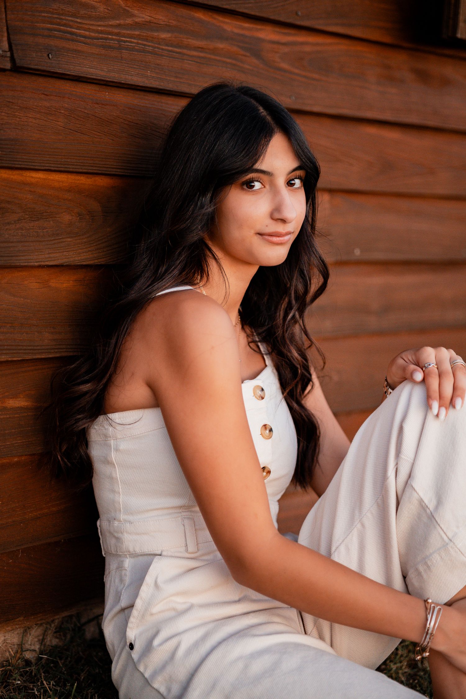 A series of portrait photos showing a person in a white dress posing against a rustic wooden wall with warm lighting.