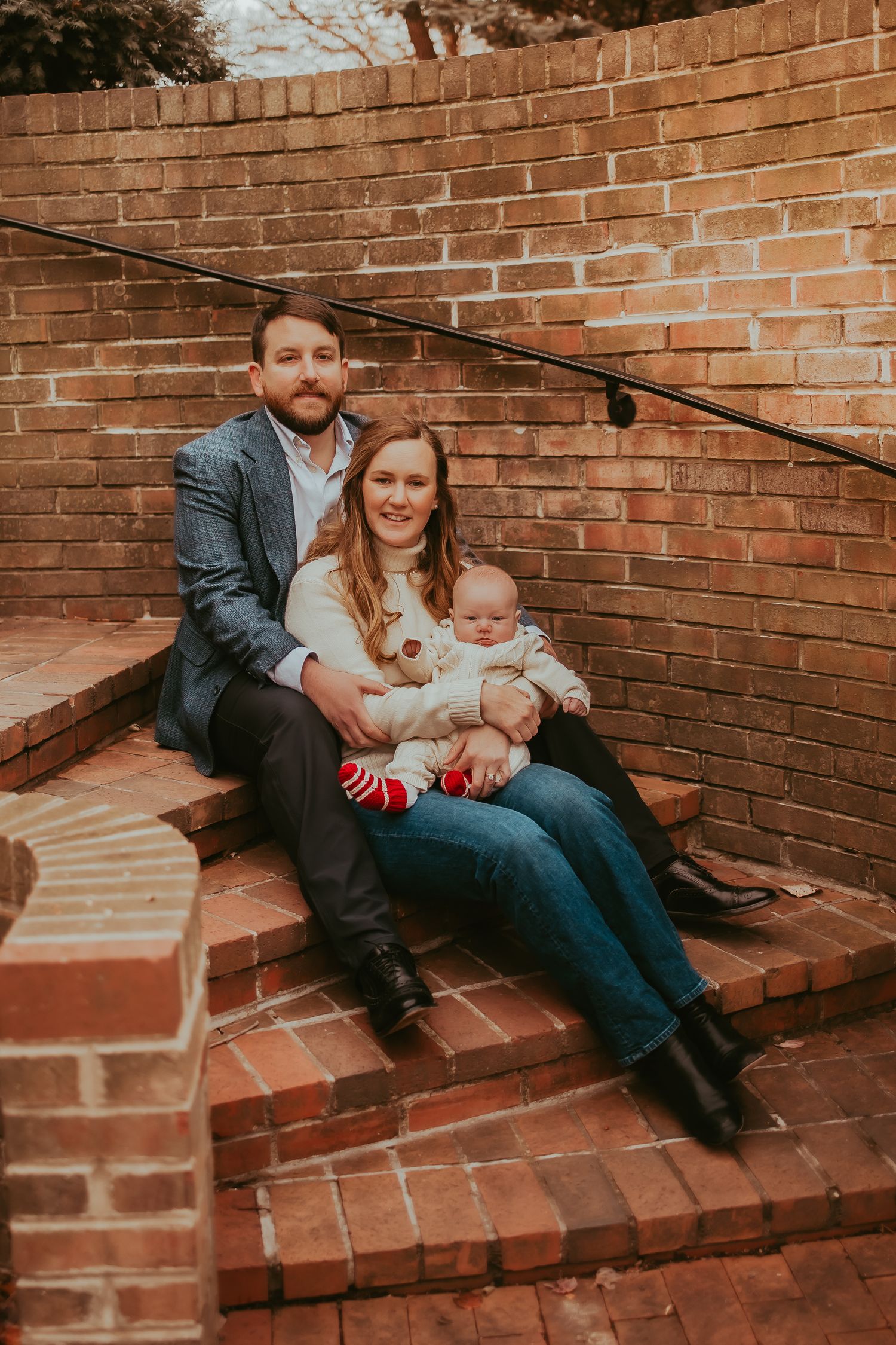A family sits together on red brick steps during an outdoor photo session.