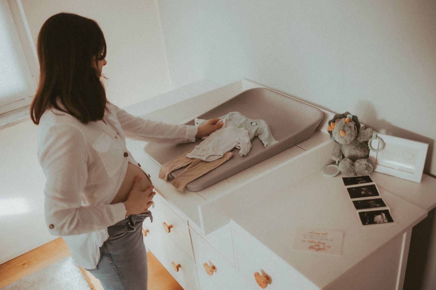 Person kneading dough on a white countertop in a bright kitchen setting.