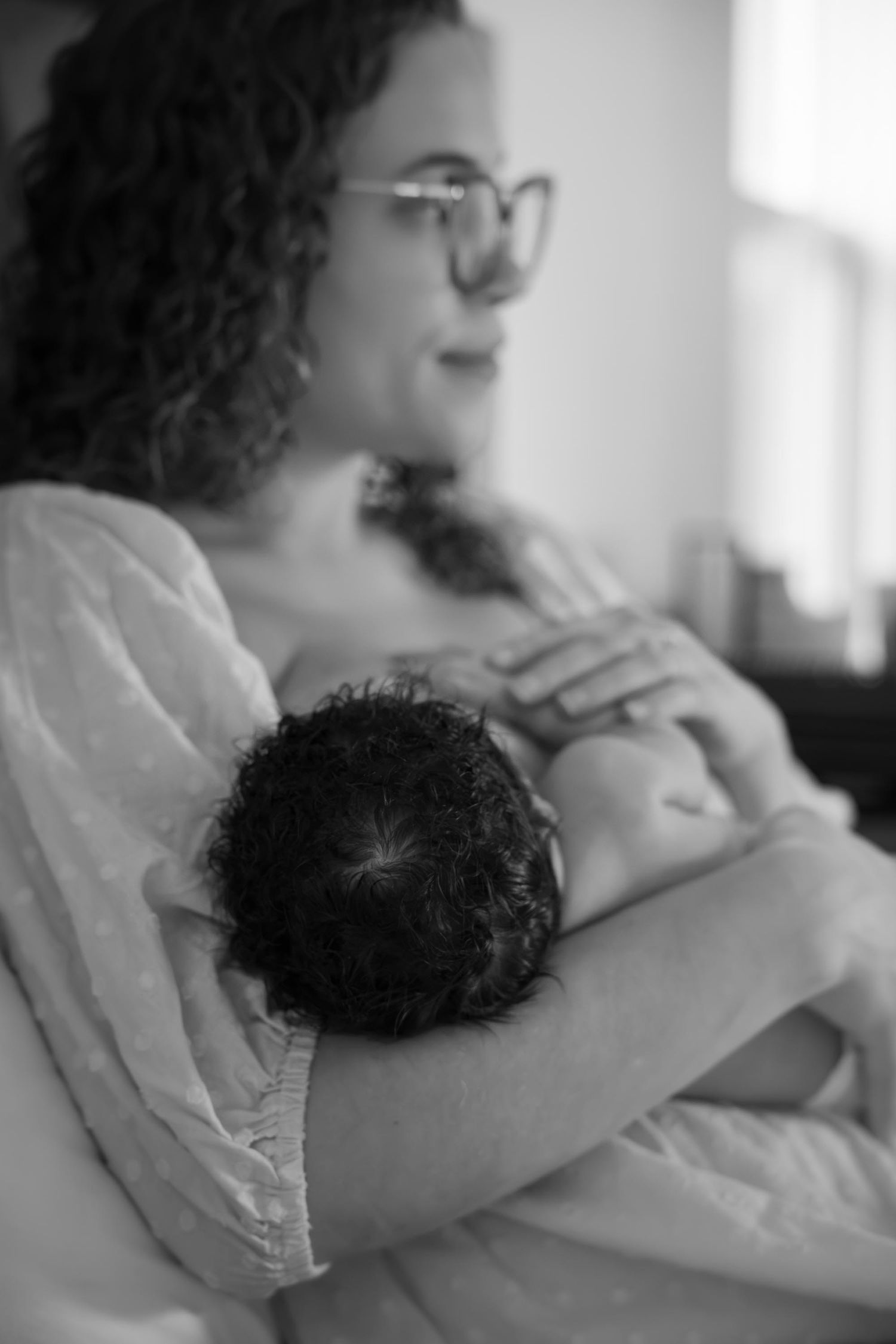 Black and white photo of a curly-haired mother cradling her newborn baby.