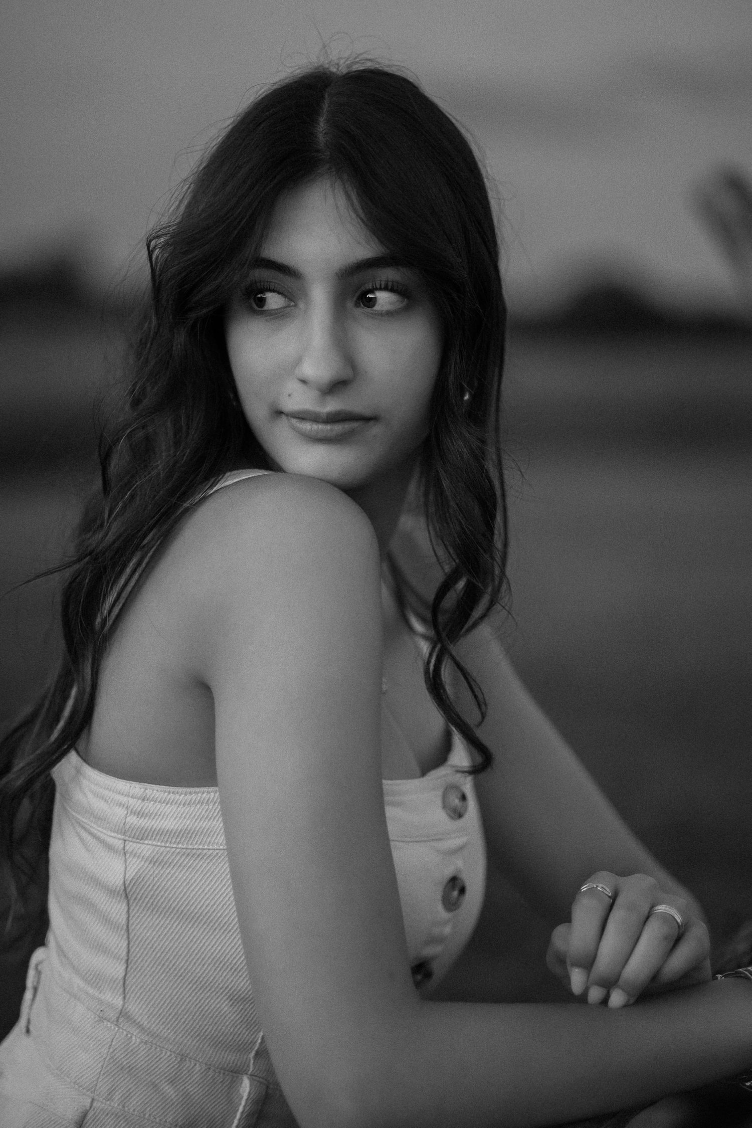 Black and white portrait of a woman with long dark hair in a white sleeveless top.