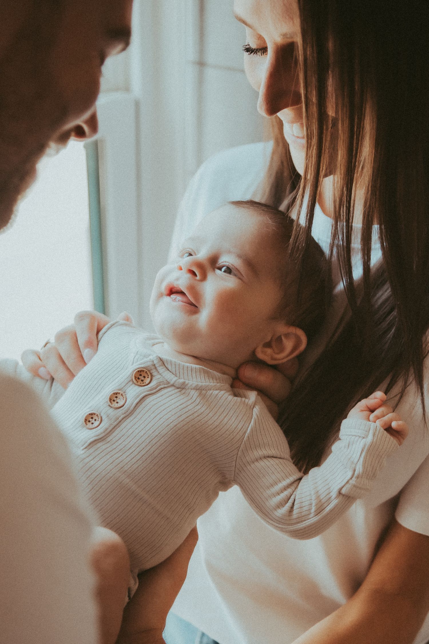 Tender close-up series showing gentle bonding moments between parent and infant in soft natural light.
