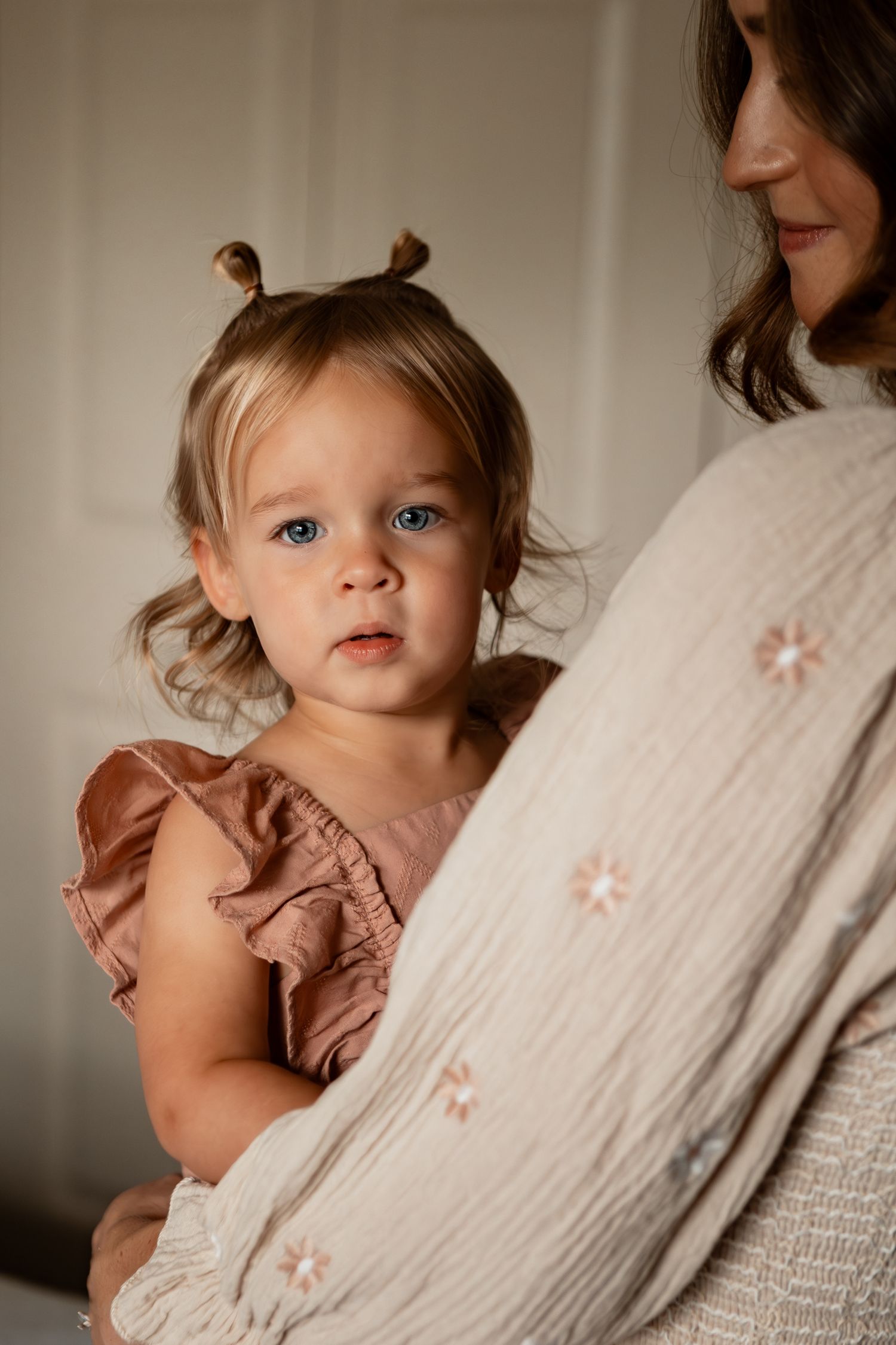 Series of intimate lifestyle portraits showing a small toddler in soft natural light wearing a dusty rose dress.