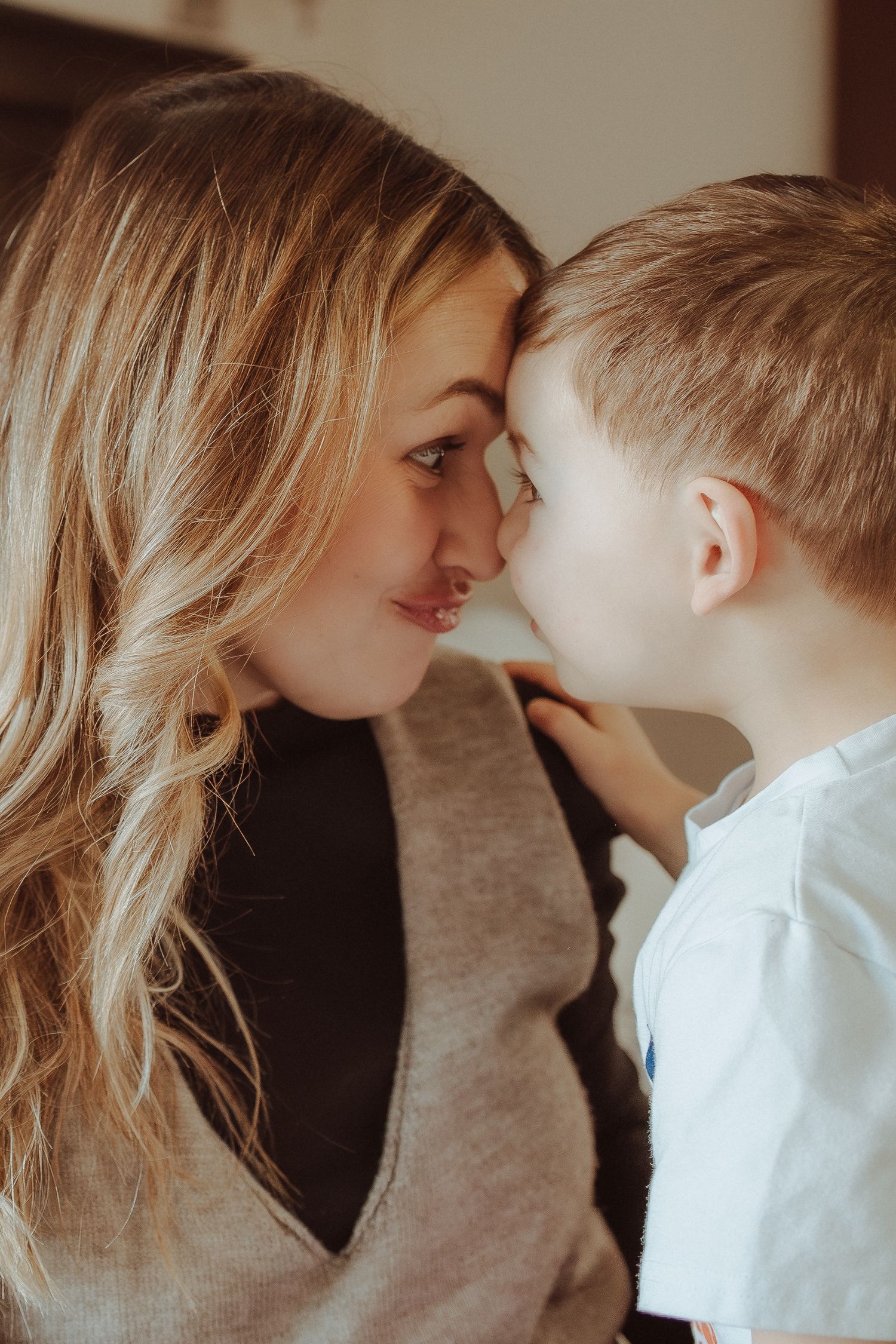 A tender moment shared between parent and child as they touch noses in warm lighting.