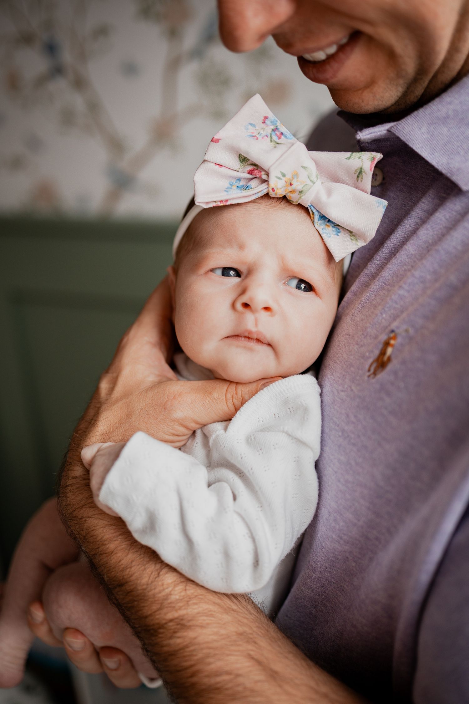 A series of intimate close-up shots showing a baby wearing a white outfit with a bow headband.