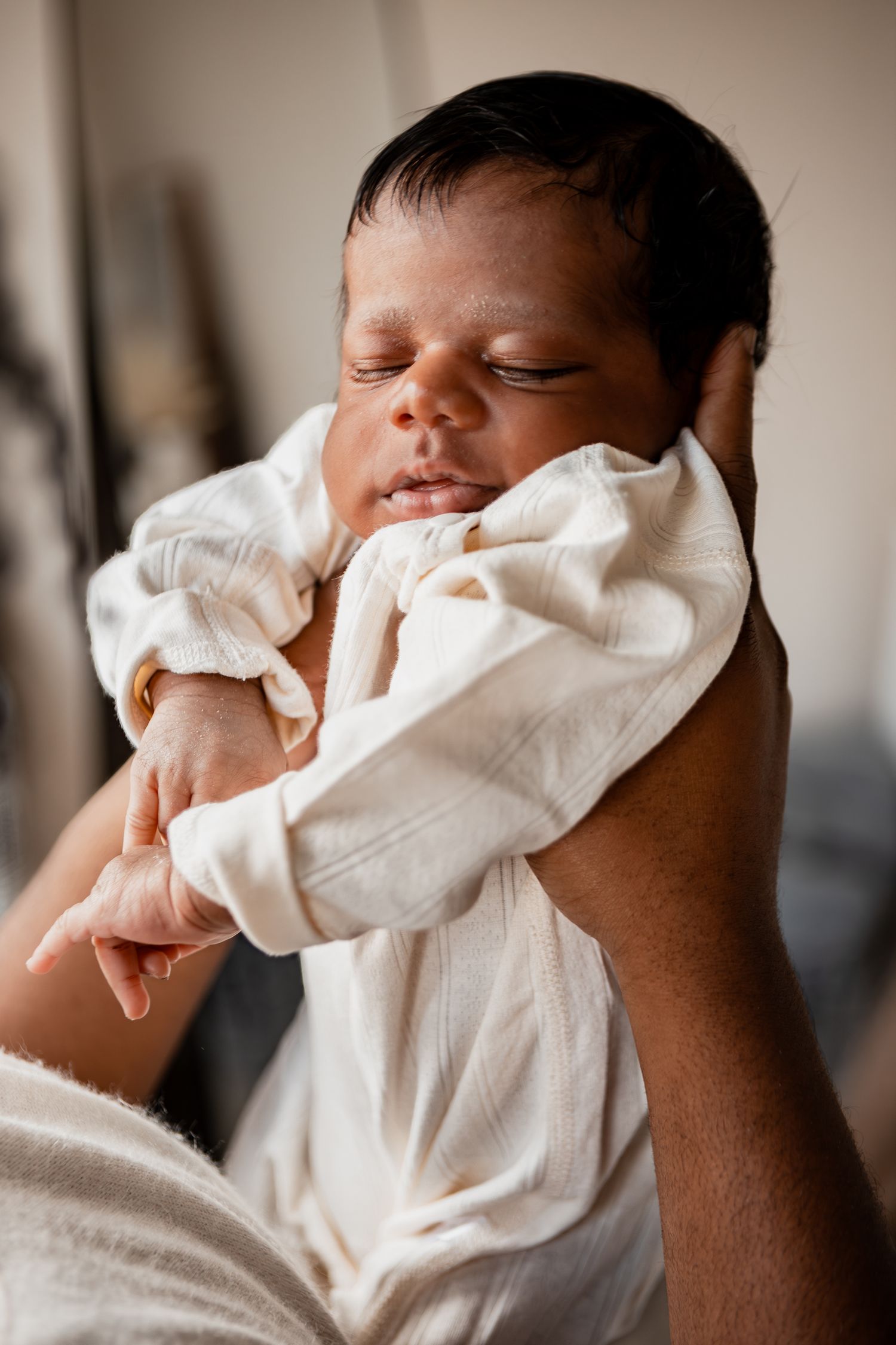 Series of gentle close-up shots showing a sleeping newborn baby wrapped in soft white fabric.