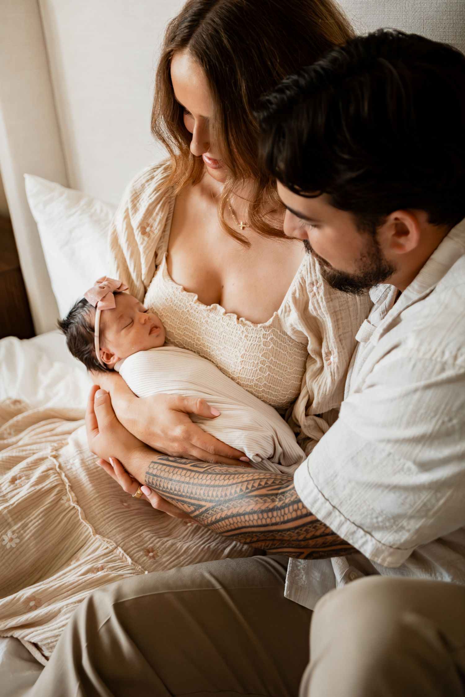 A series of four intimate newborn family photos showing tender moments in neutral tones on white bedding.